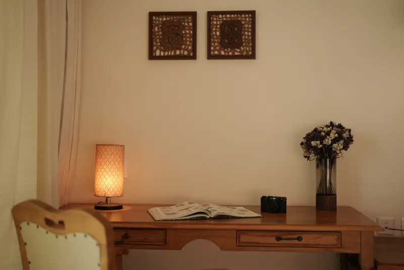 Writing table in a Paddy Field View Room at Vedic Village Alleppey with a bedside lamp, fresh flowers and reading material