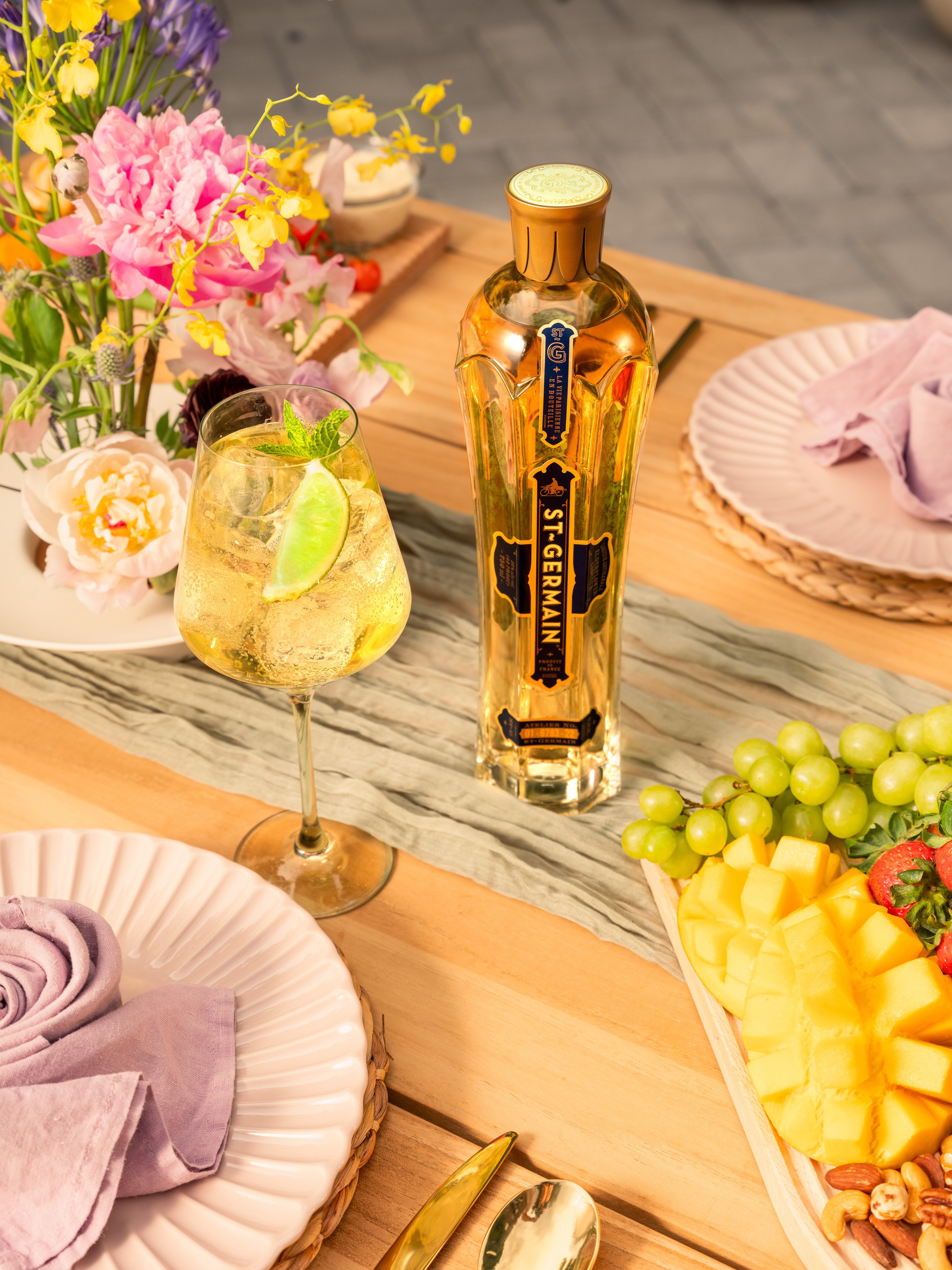 Overhead St Germain bottle, fruit, florals, and lavender table linens