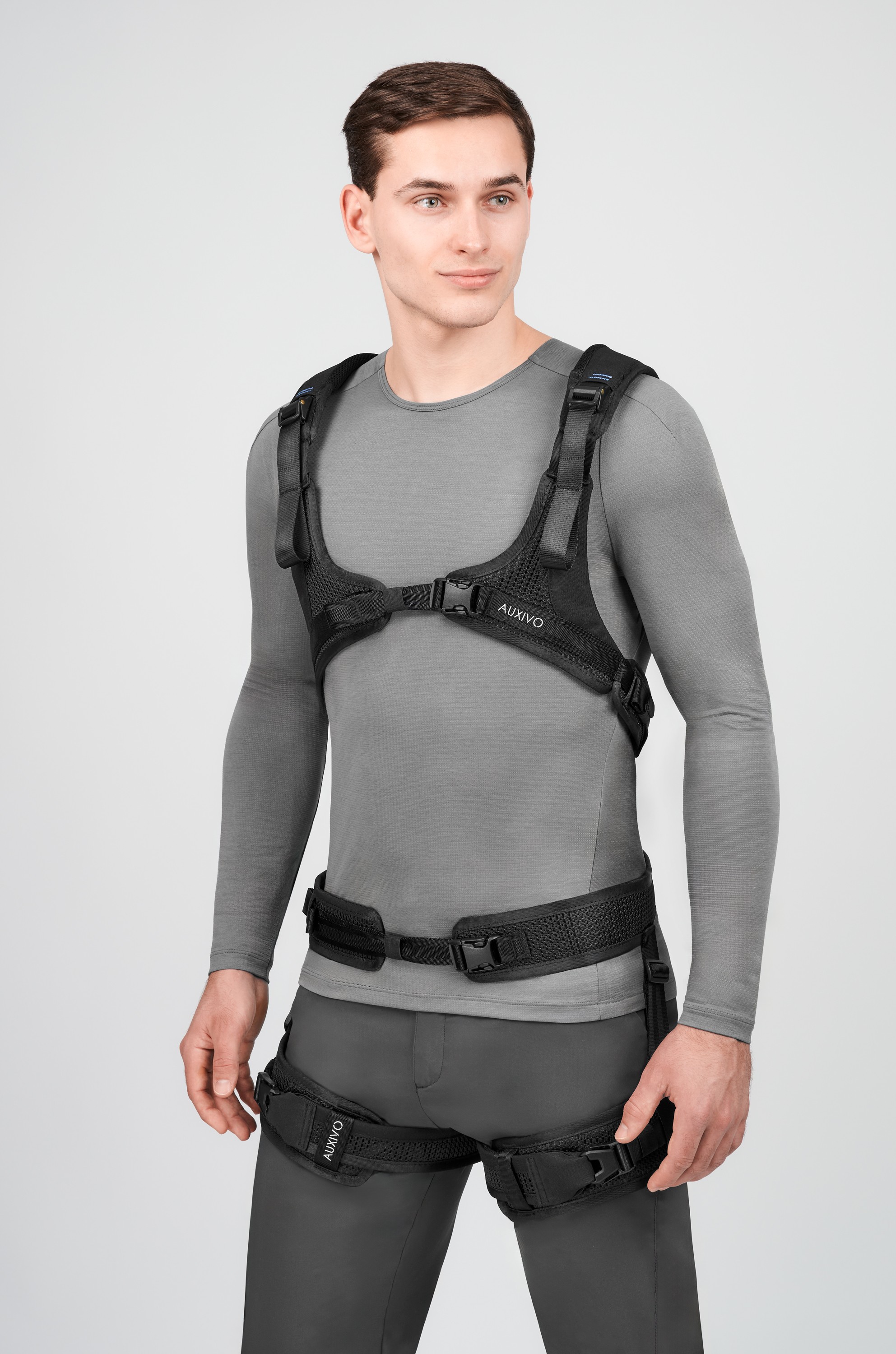 User wearing the Auxivo LiftSuit exoskeleton seen from the front, with chest and hip straps ensuring a stable and comfortable fit.
