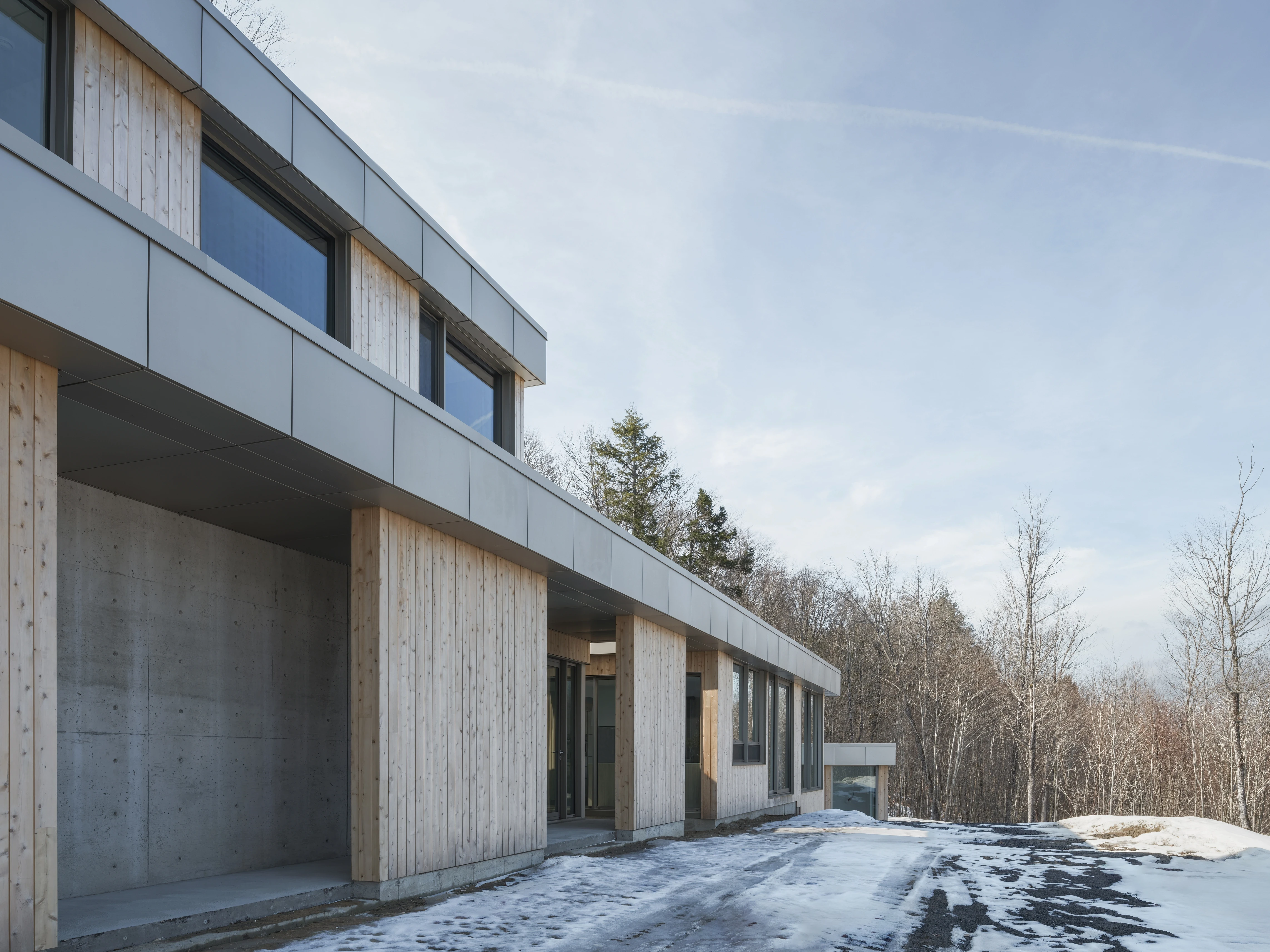 Architectural facade in nature – A minimalist home with raw concrete and wood cladding, harmonizing with the snowy environment.