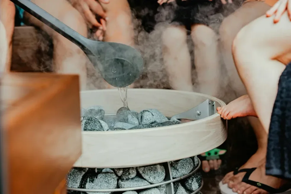 Pouring water onto hot coals in sauna
