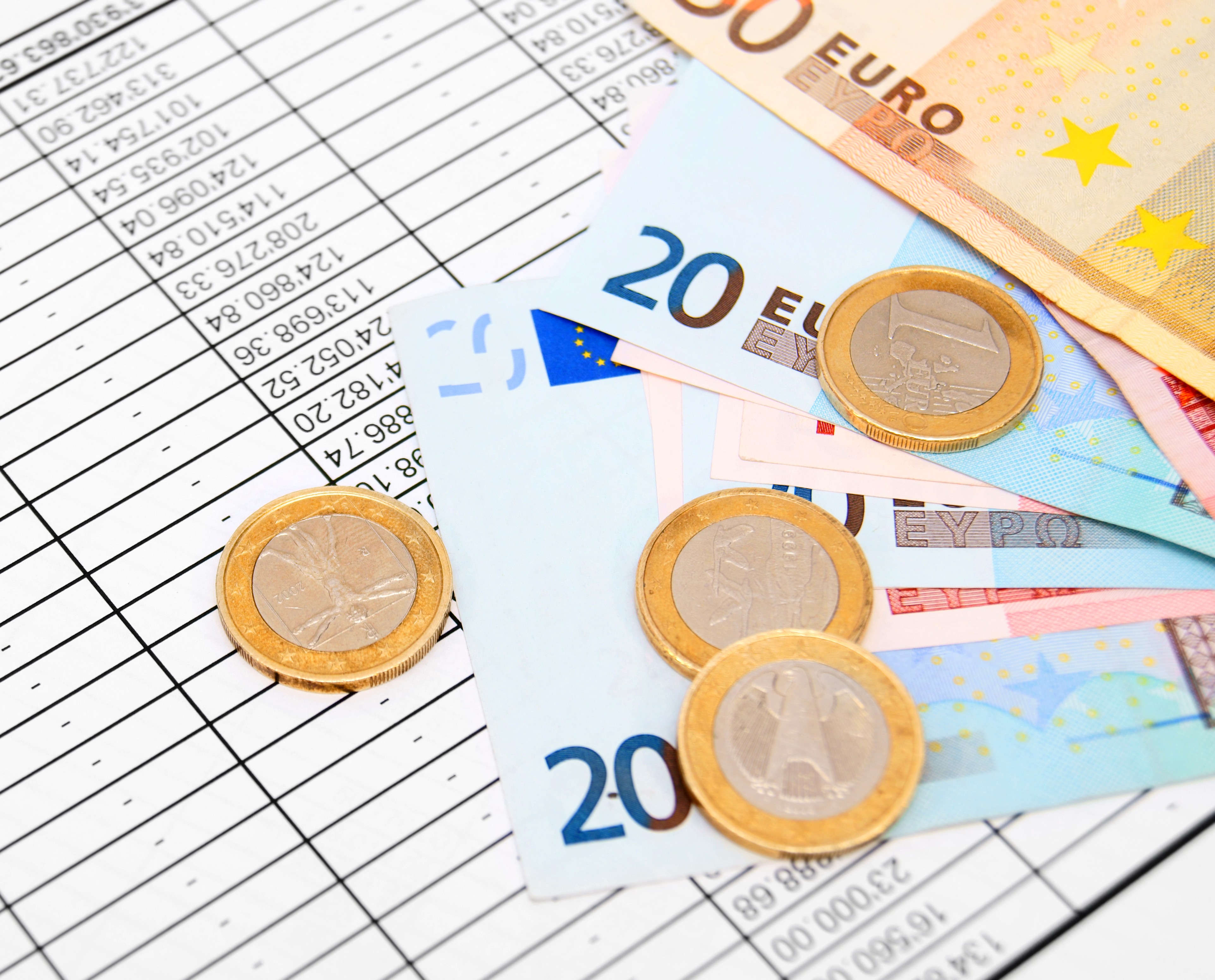 Eurobiljetten en munten op belastingformulieren, symbool voor belastingadvies en fiscale emigratiebegeleiding.