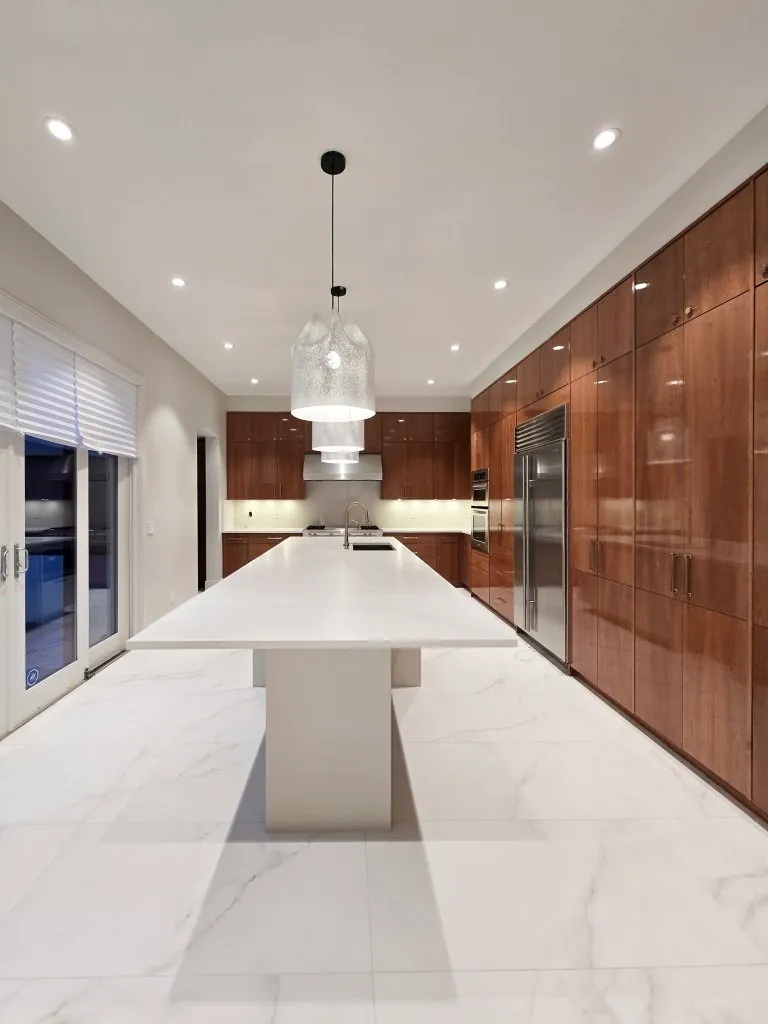 Image of KHD Homes kitchen design with large island, wood cabinets, and modern lighting fixtures layout design.