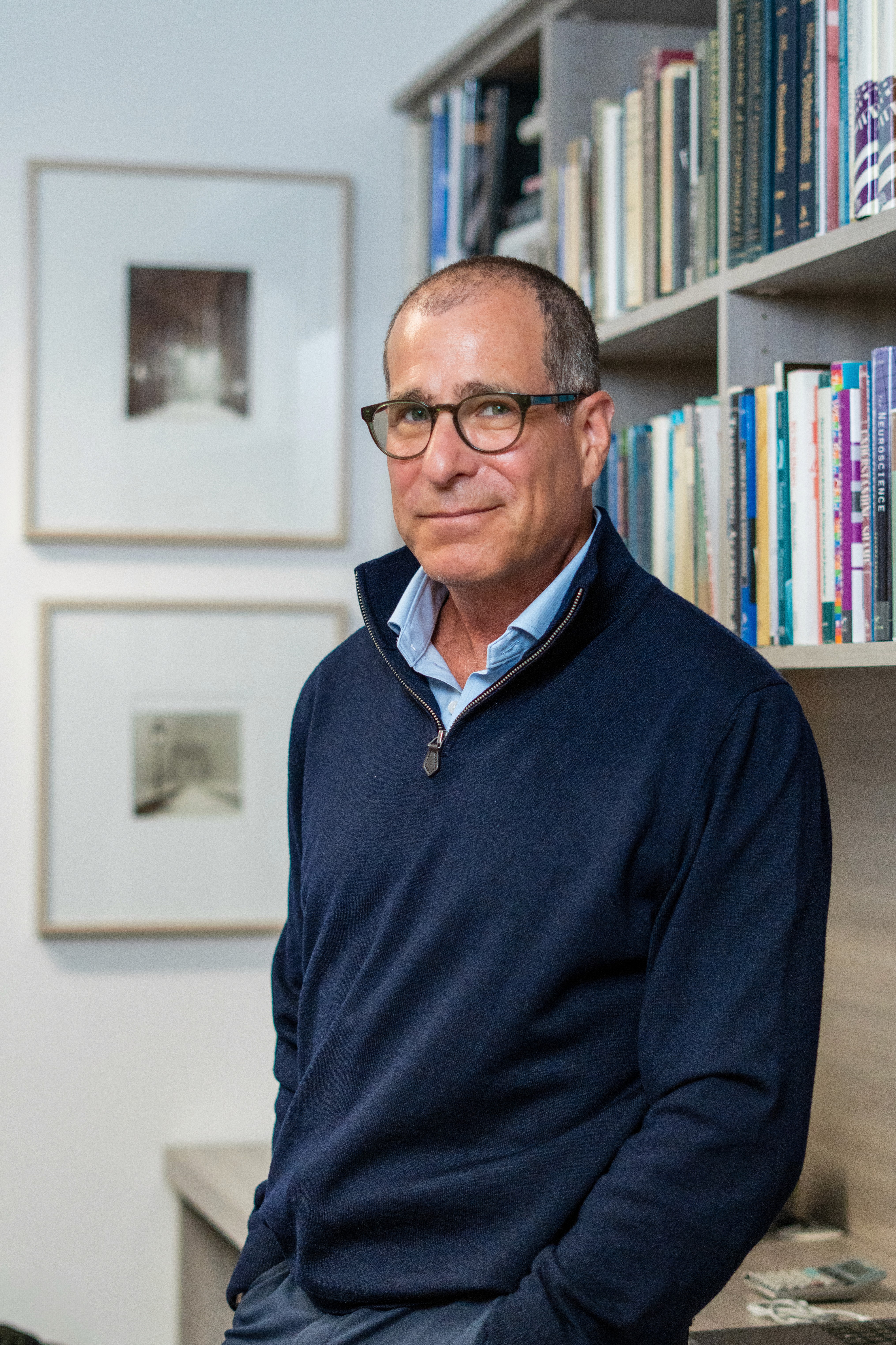 Image of marc sholes standing near bookshelves