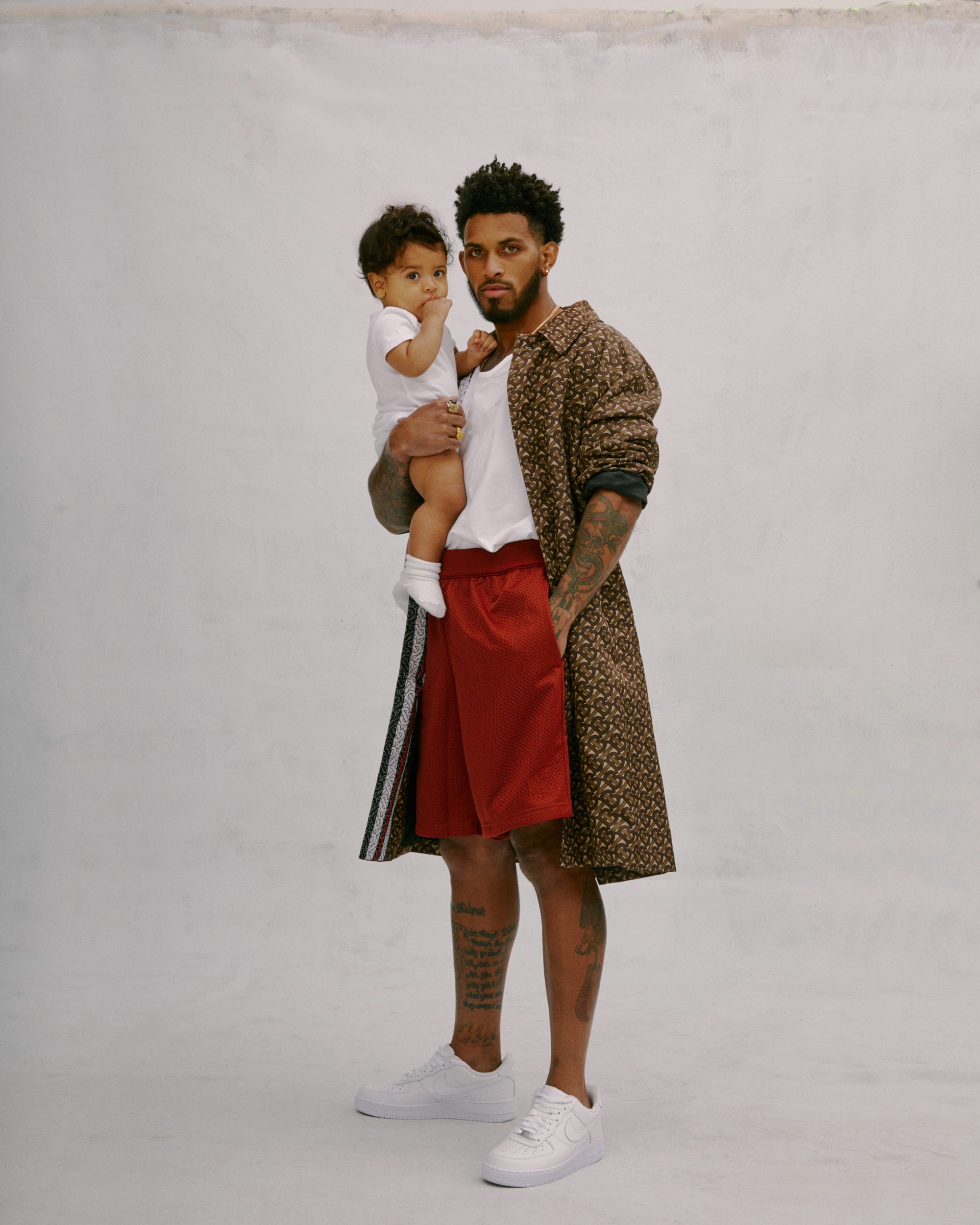A man stands holding a small child against a neutral background.