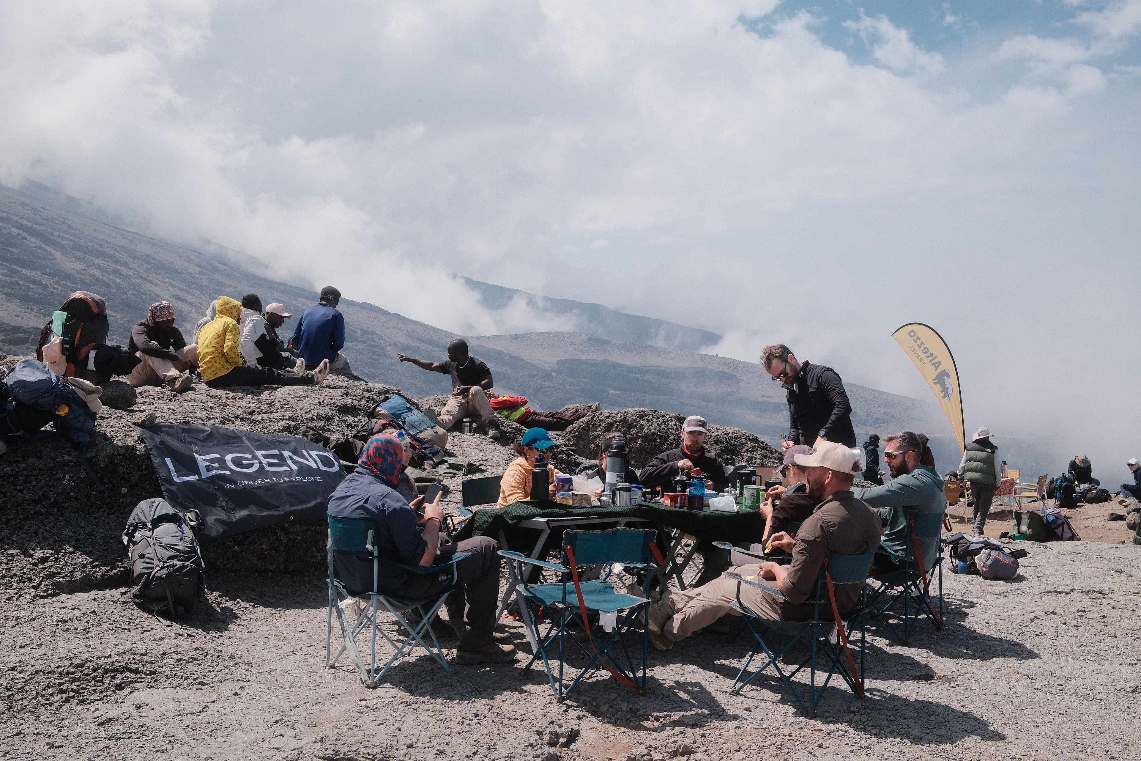 A Kilimanjaro climber resting and hydrating at camp while managing mild altitude sickness symptoms.