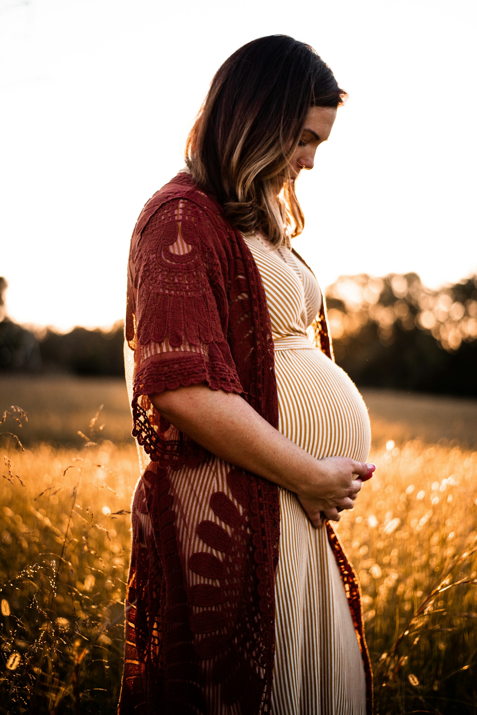 Expecting mother in a golden field at sunset
