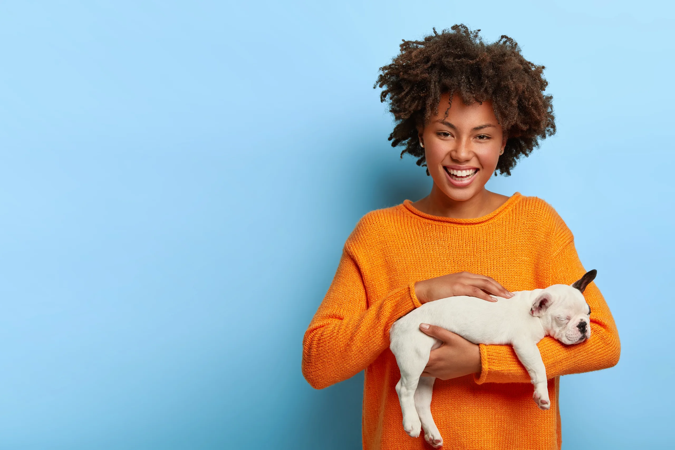 mulher com roupa laranja segurando cachorro com sorriso