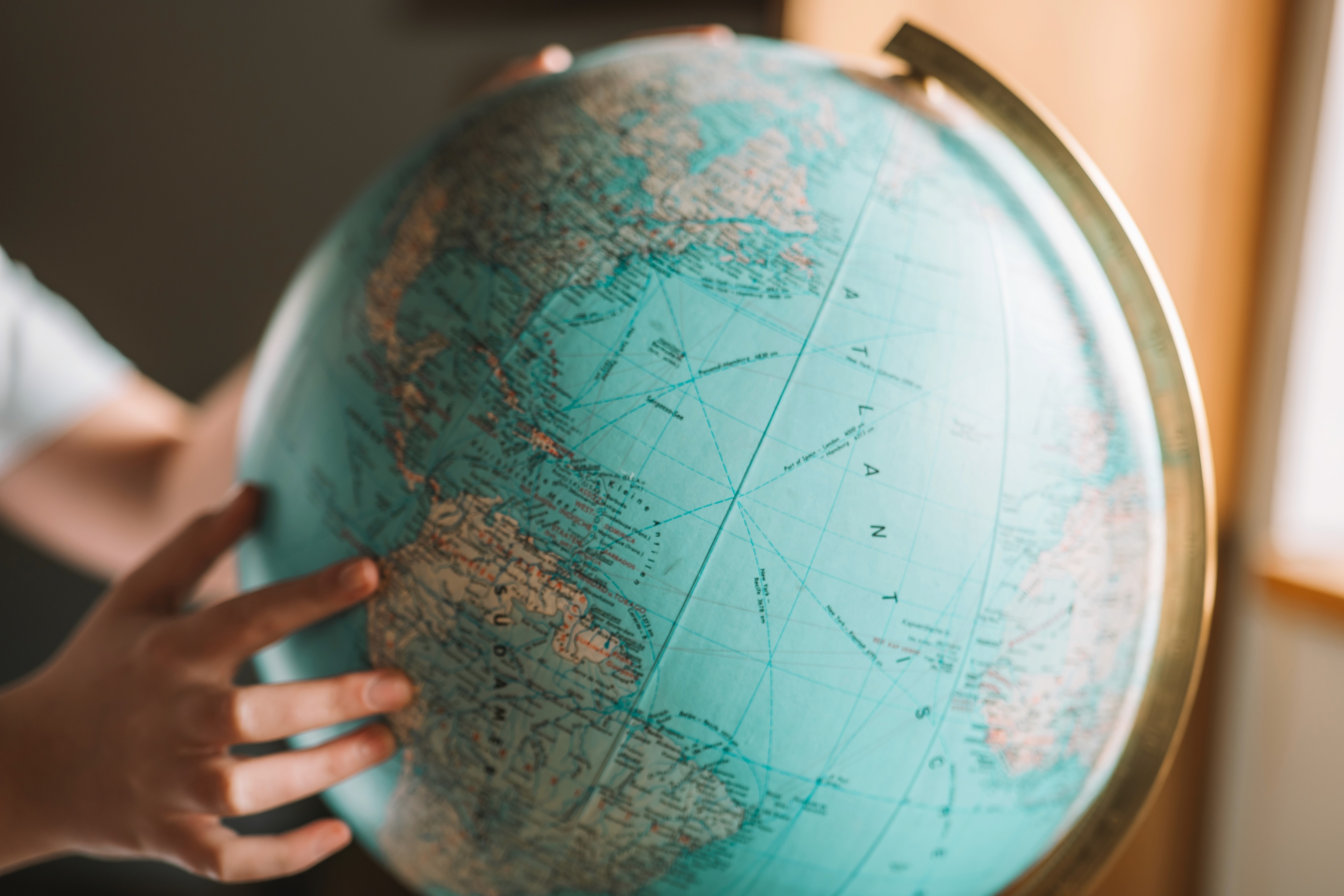 Hands holding a globe, pointing at a country in South America