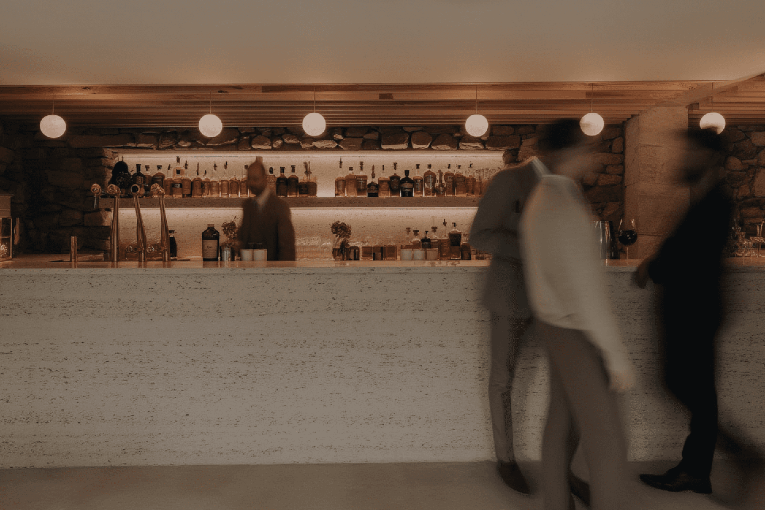 Atmospheric bar with backlit bottle display and standing guests