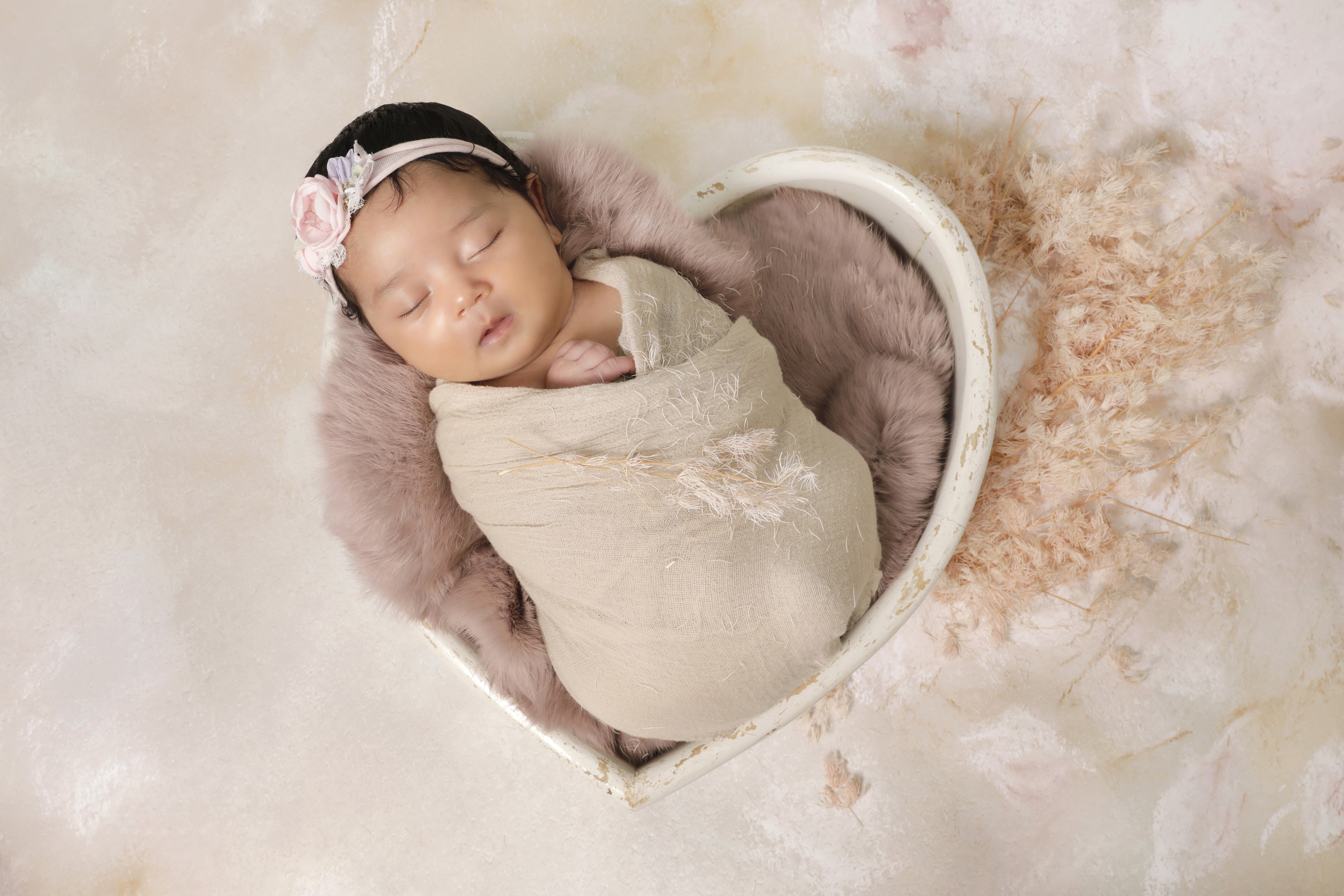 A newborn swaddled in a heart-shaped basket