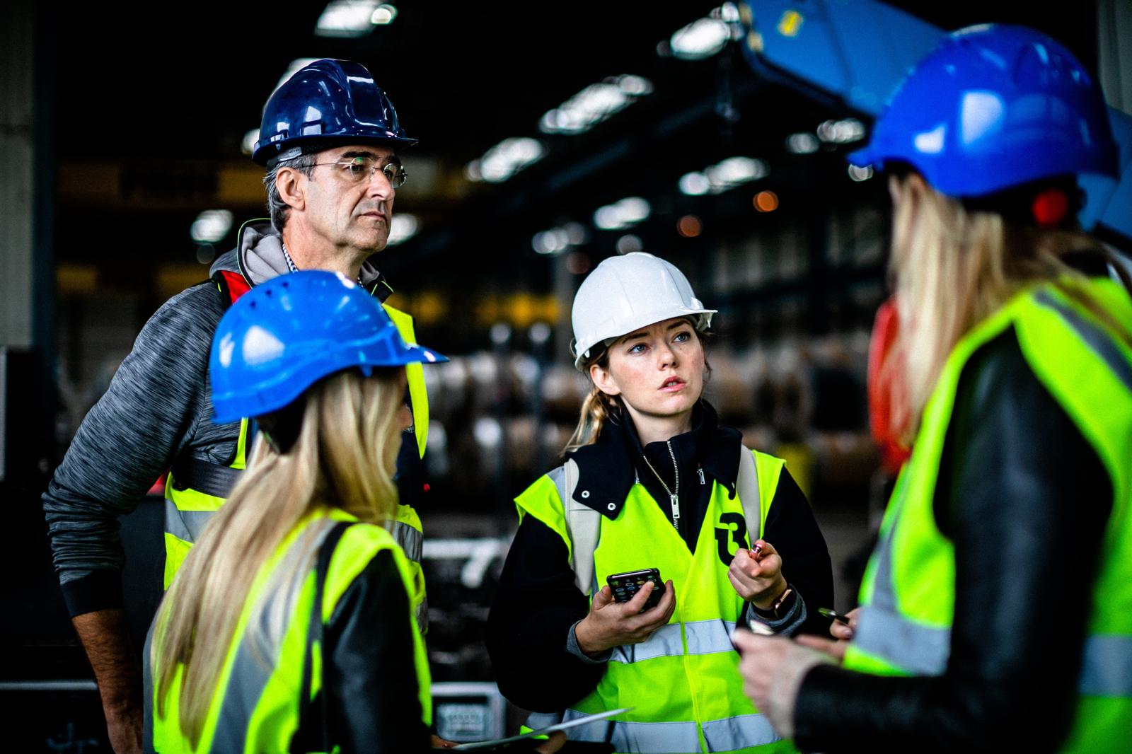 Rachel in a white hard hat speaking with a group on an industrial site.