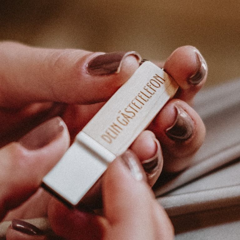 Gästetelefon-Stick mit den gesammelten Sprachnachrichten in der Hand