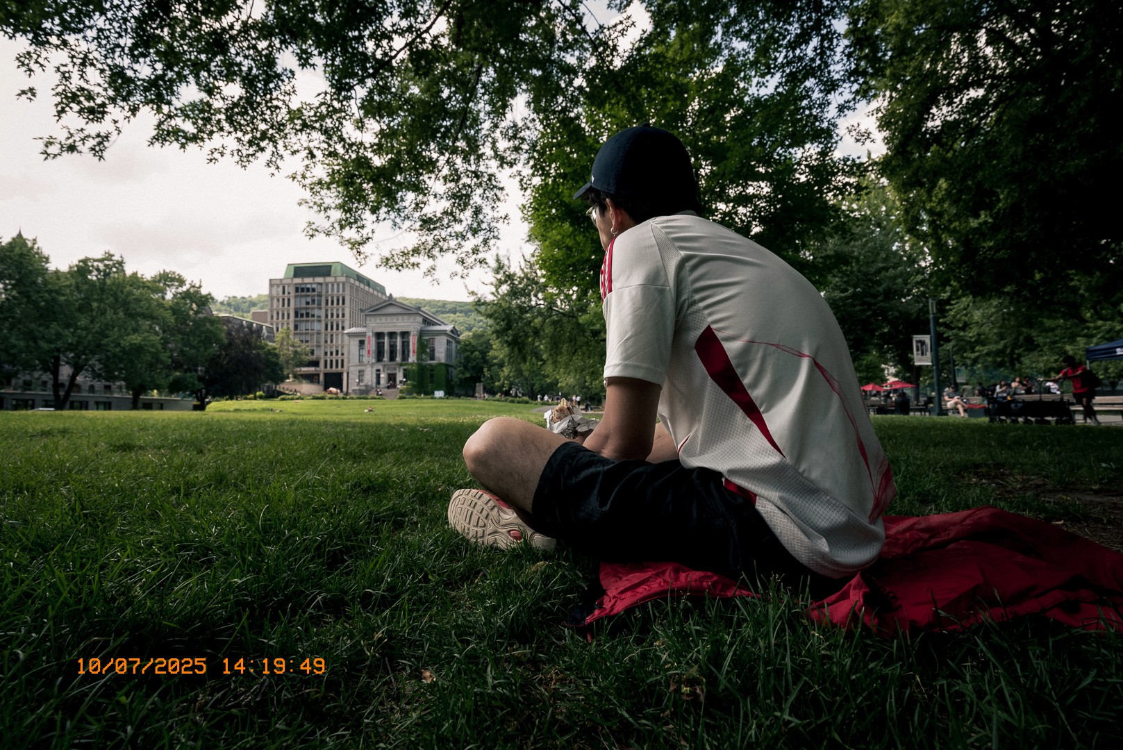 Jeune homme assis sur l’herbe face au bâtiment principal de l’université McGill.