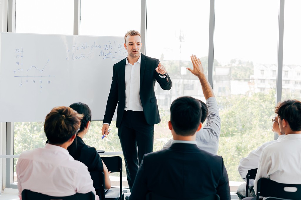 man standing in front of people sitting beside table with laptop computers