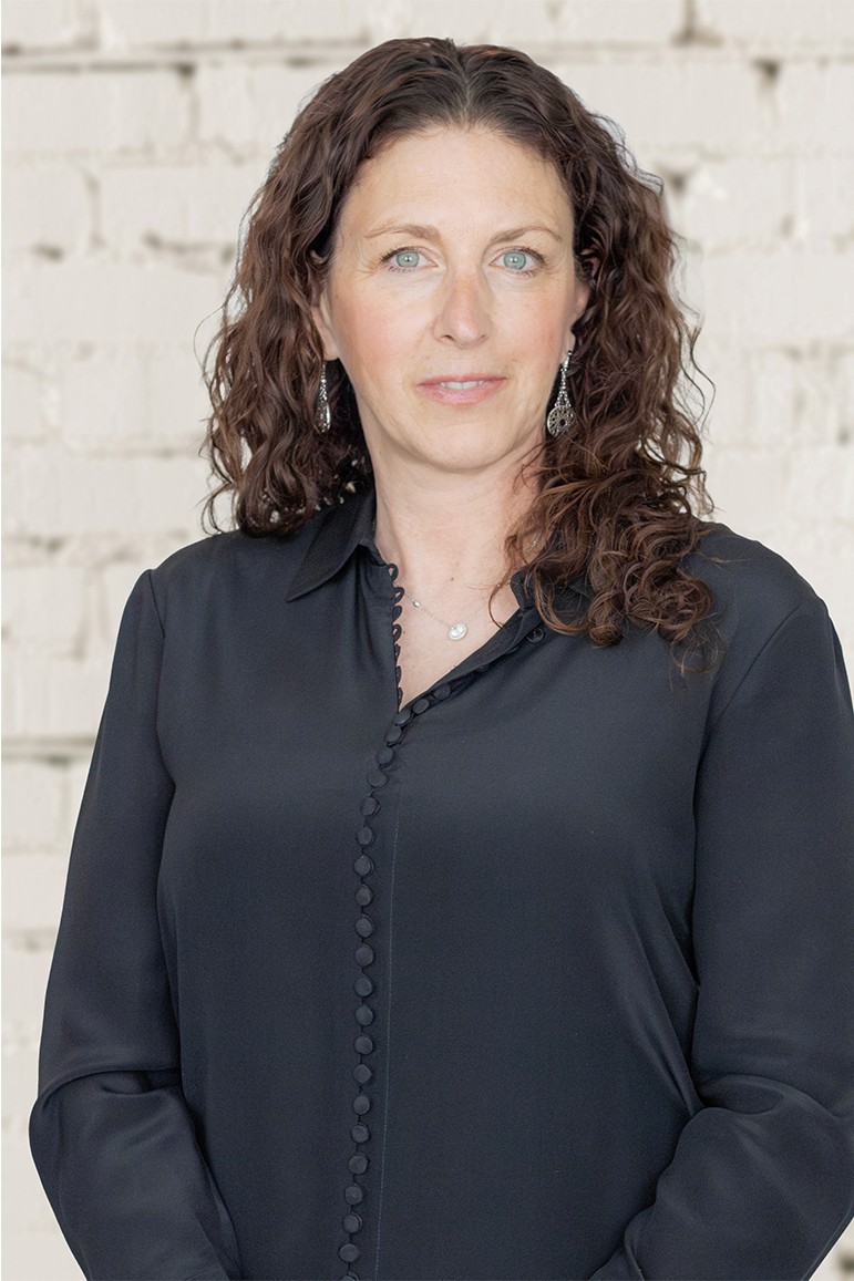 Image of a fair skinned woman with auburn hair and piercing green eyes smiling at the camera.