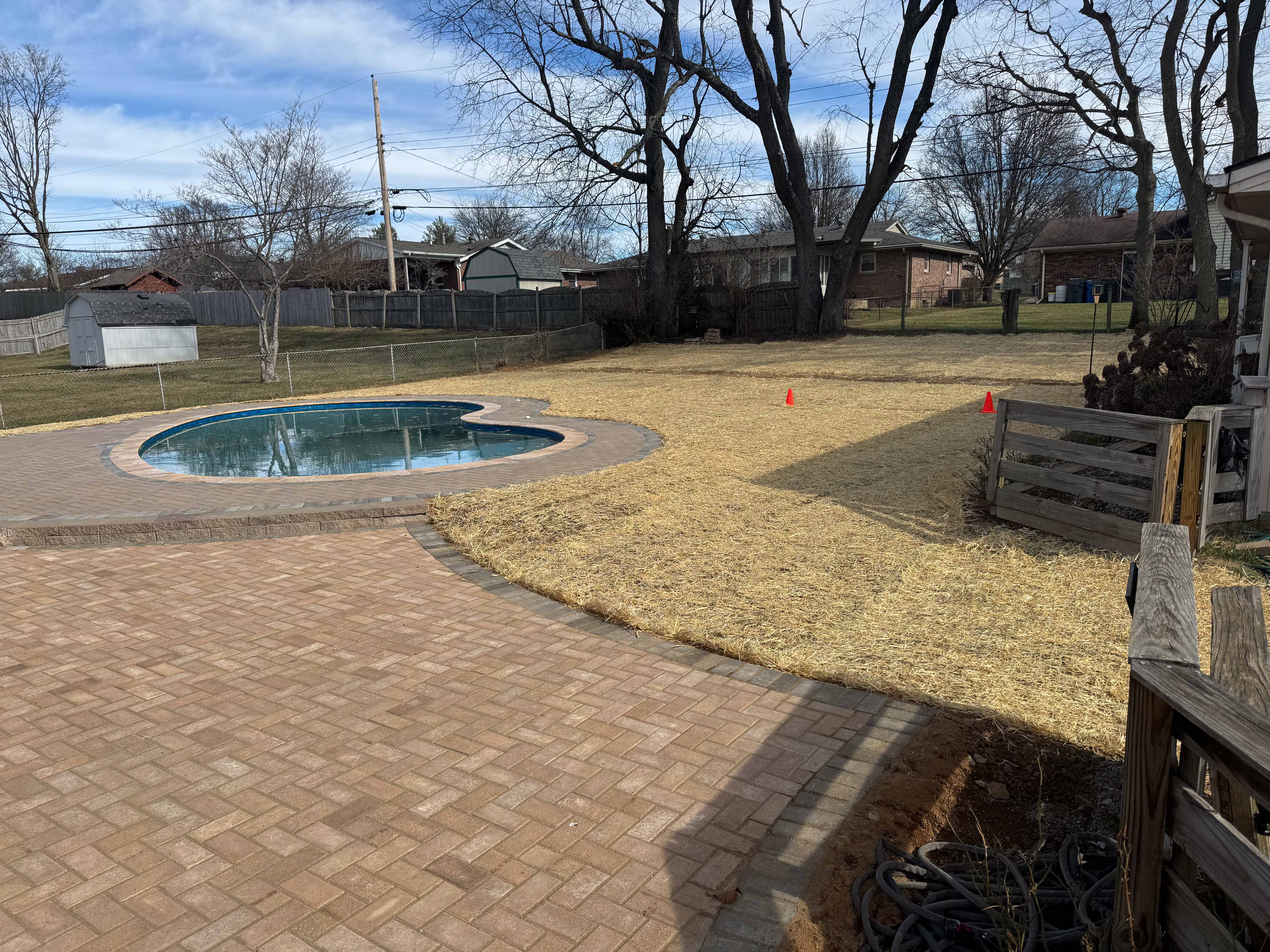 Completed pool hardscape with straw-seeded lawn prep