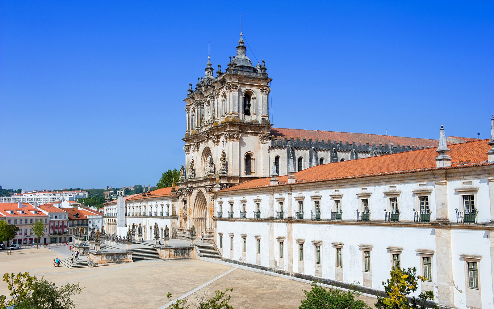Portekiz'deki Alcobaça Manastırı'nın süslü cephesi ve çevresinde avlusu bulunan dış görünüşü.