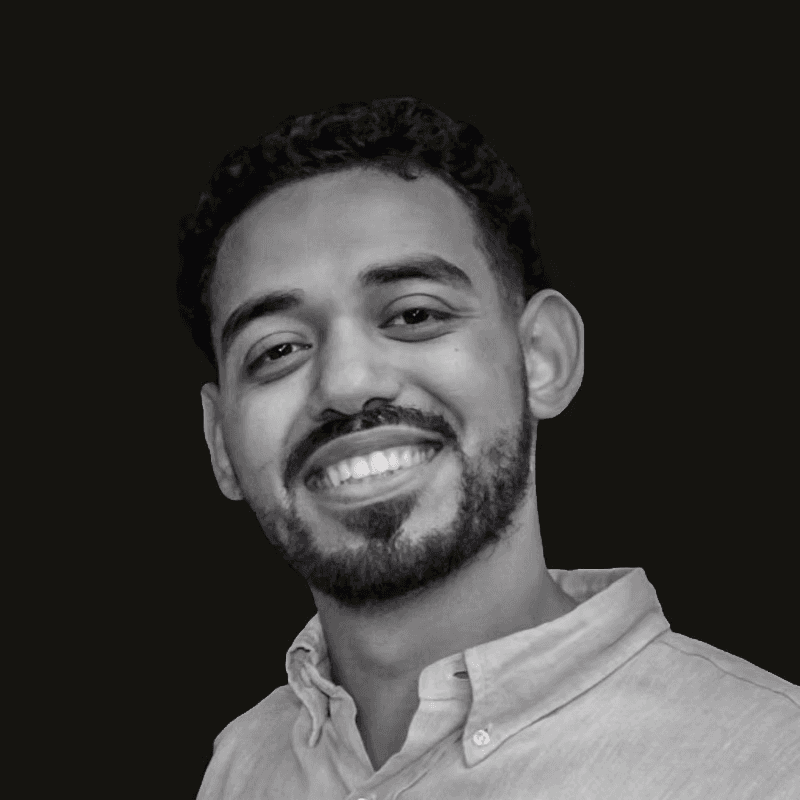 Woman wearing orange-tinted sunglasses and many gold necklaces.
