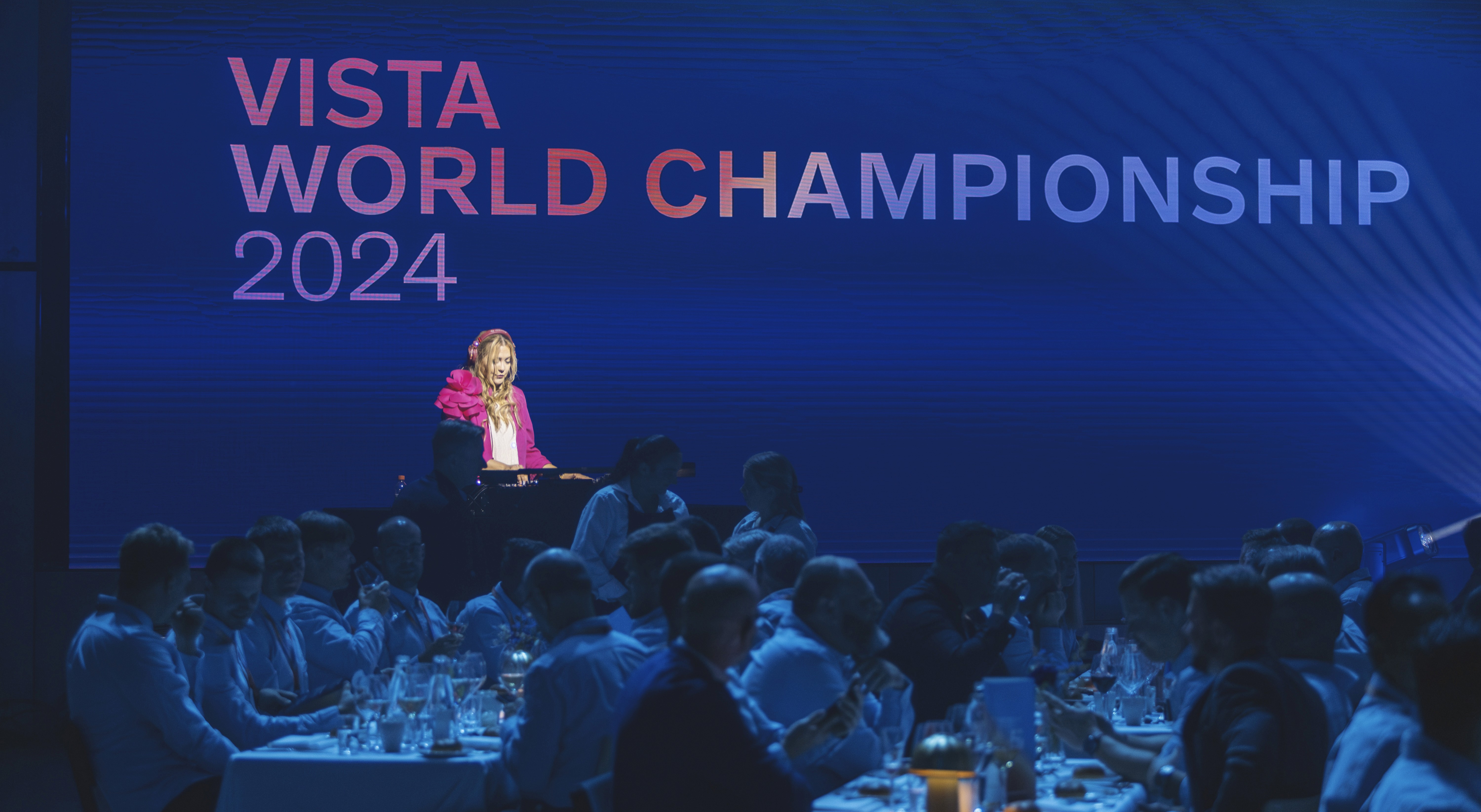 A presenter standing on a stage in front of a large crowd