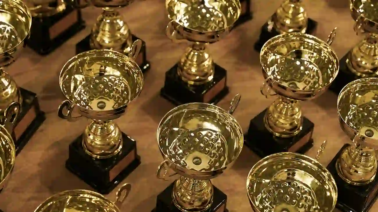 Rows of gold trophies displayed on a table at a sports event, representing tournament sponsorship, measurable event activations and sponsor reporting for sports clubs.