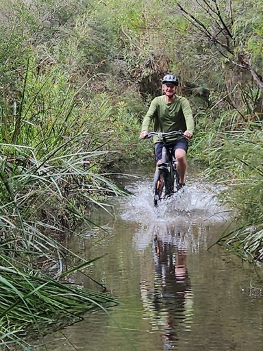 Middle aged man having fun crossing an easy puddle during a bicycle bush ride