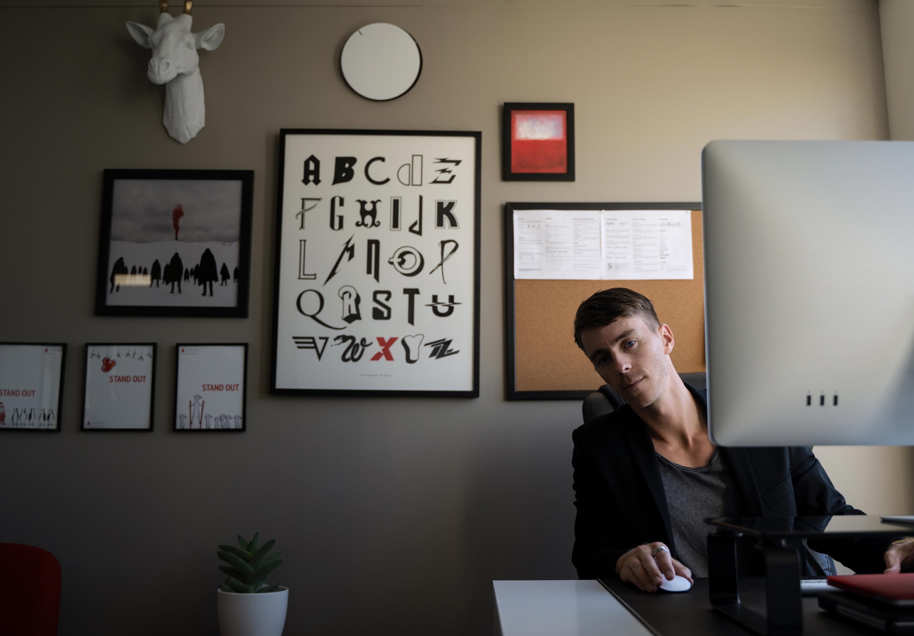 Max at his desk, leaning over from behind his monitor