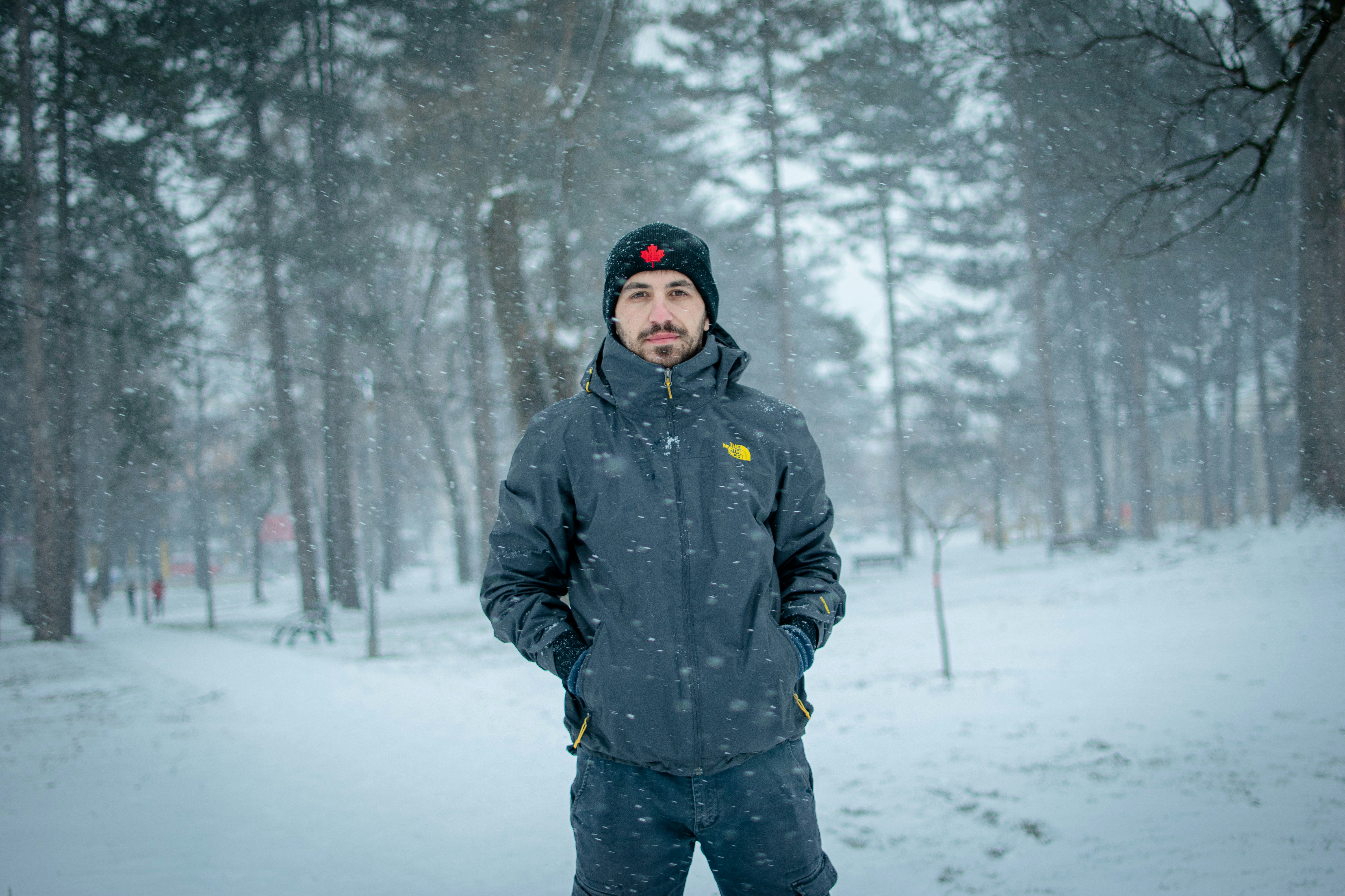man in black jacket standing on snow covered ground