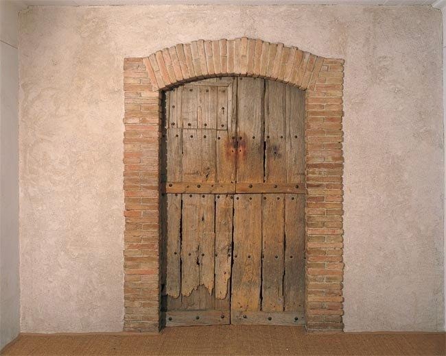 A wooden door in a wall
Description automatically generated