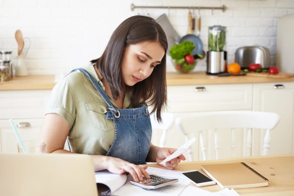 Woman sitting at kitchen table working on budget.
