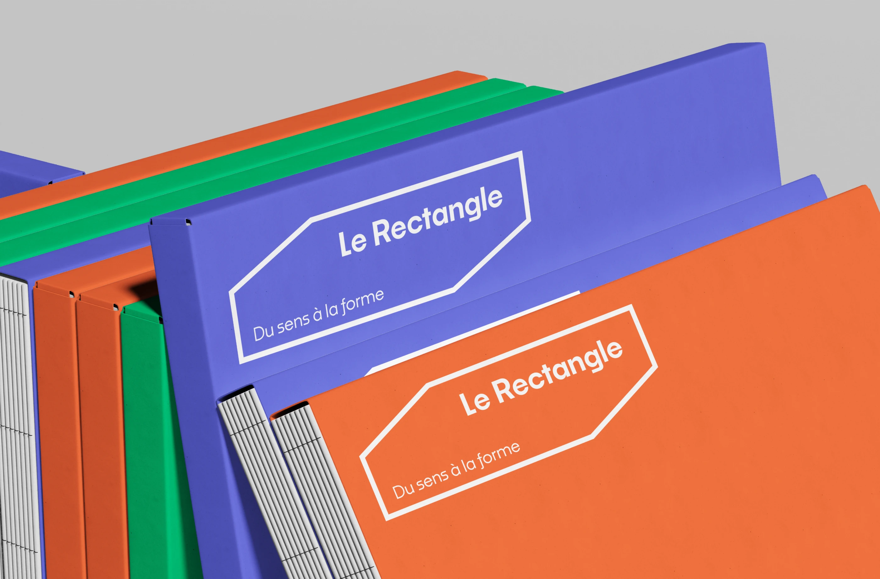 Série de classeurs d'édition colorés (bleu, vert, orange) floqués du logo Le Rectangle avec reliure apparente.