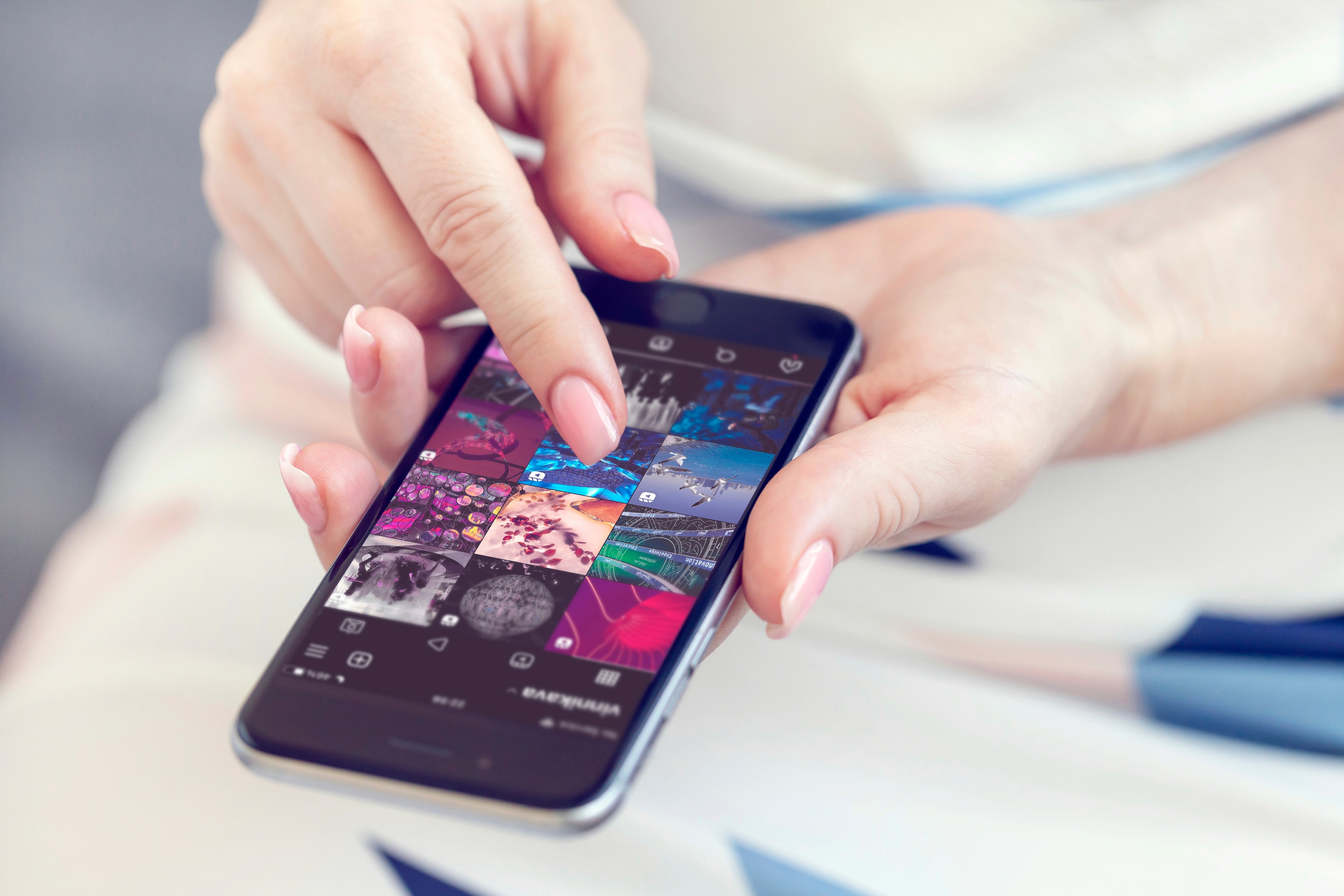 Woman scrolling through her Instagram feed on a smartphone, representing how social media platforms play a key role in video marketing strategies to drive engagement and sales in 2025.