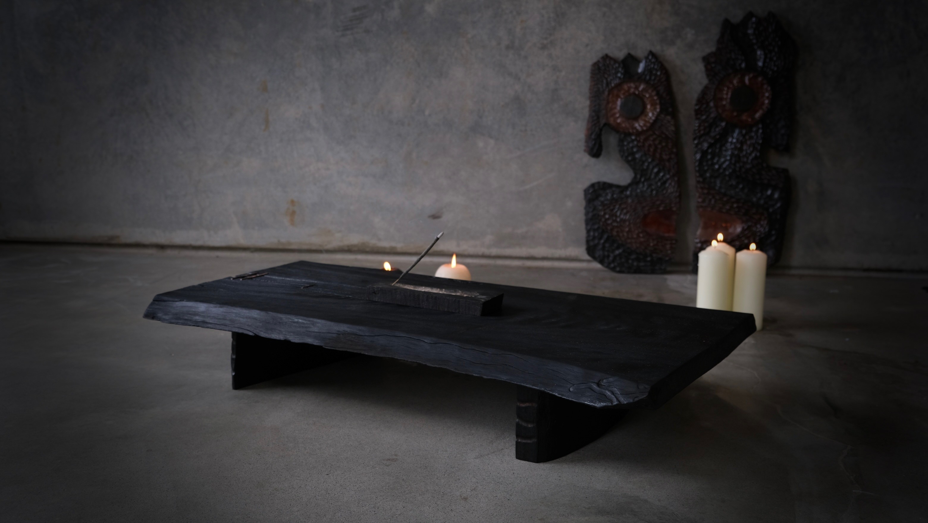Charred timber tea table in a candlelit studio