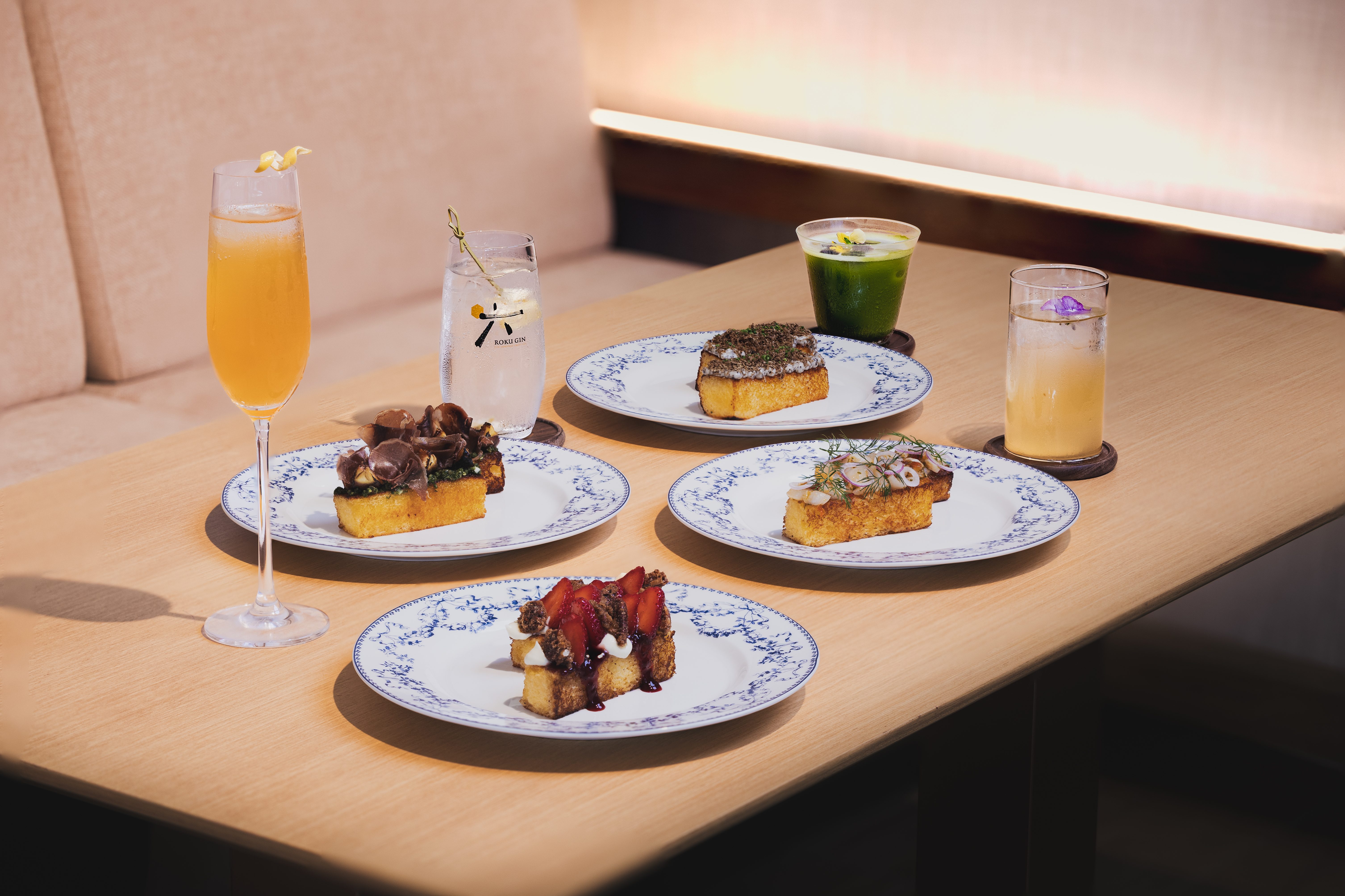 A beautifully arranged table featuring various delicacies, including small toasts topped with different ingredients and a selection of drinks. The setting exudes an elegant atmosphere.