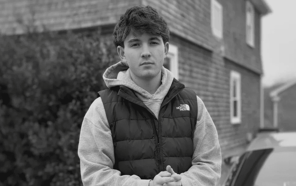 Portrait of a man with short dark hair and a trimmed beard, dressed in a dark shirt, on a simple background.