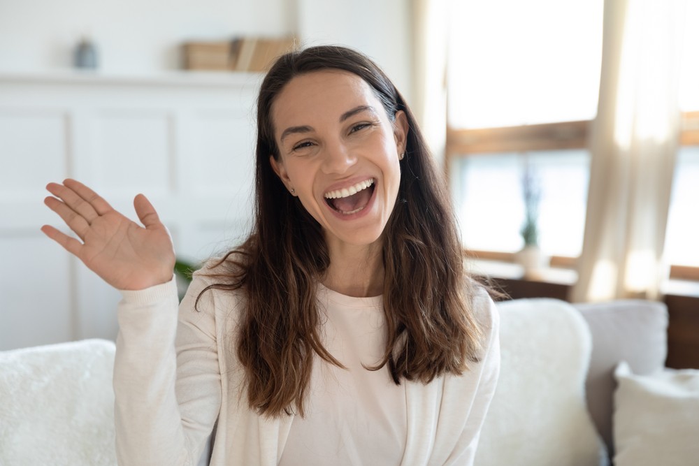 woman in yellow tee waving to camera