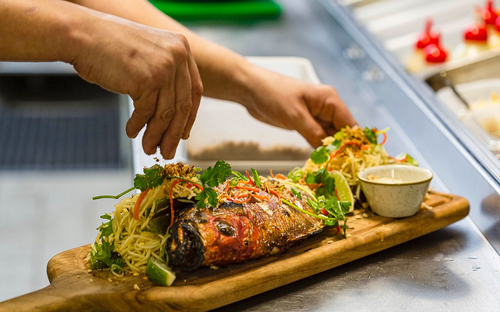 Gourmet fish dish being prepared on a wooden board during a culinary tour.
