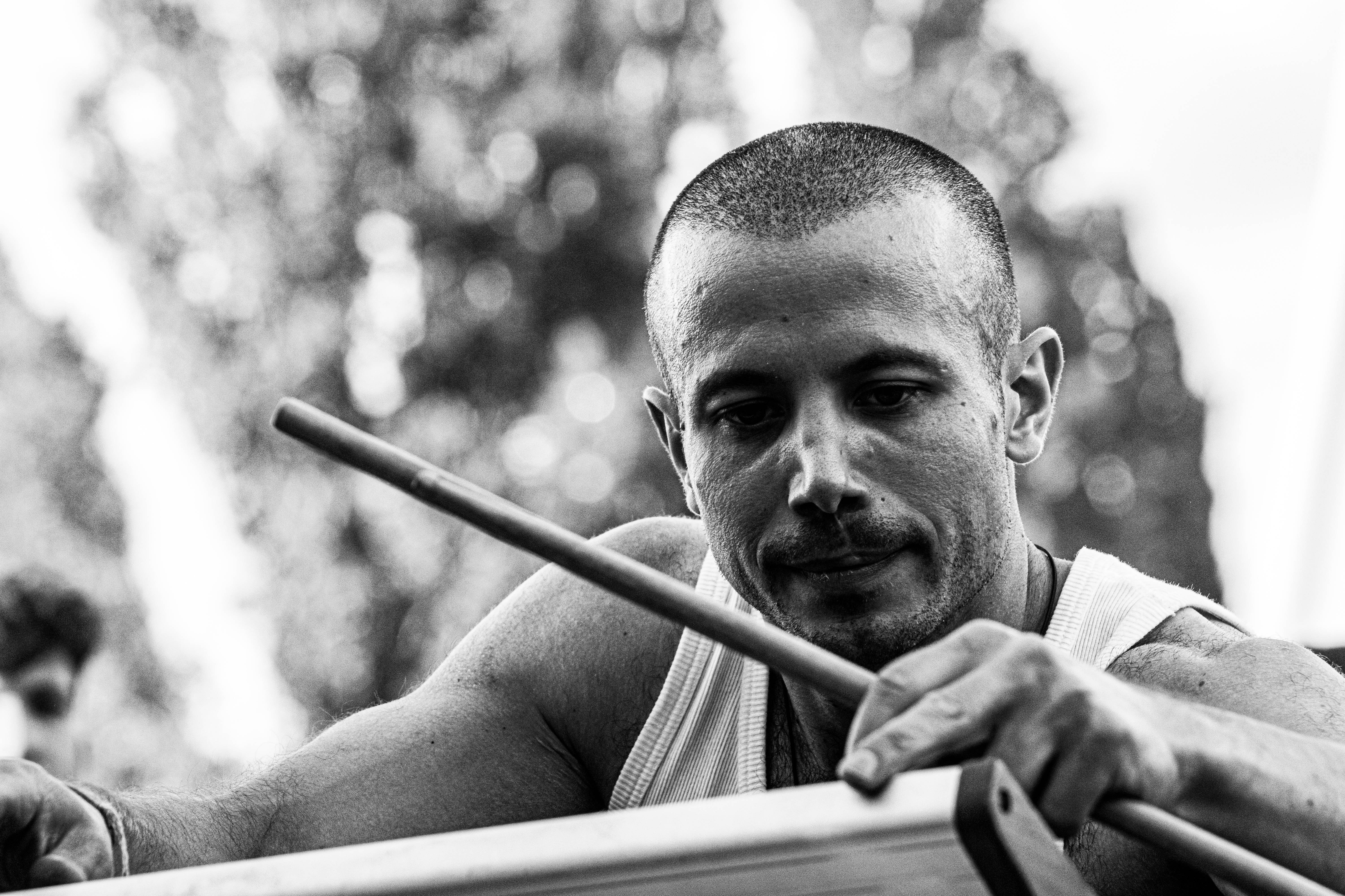 Man playing a hand drum outdoors with focused attention, illustrating rhythm, movement, and sensory engagement as pathways to nervous system regulation and embodied awareness.