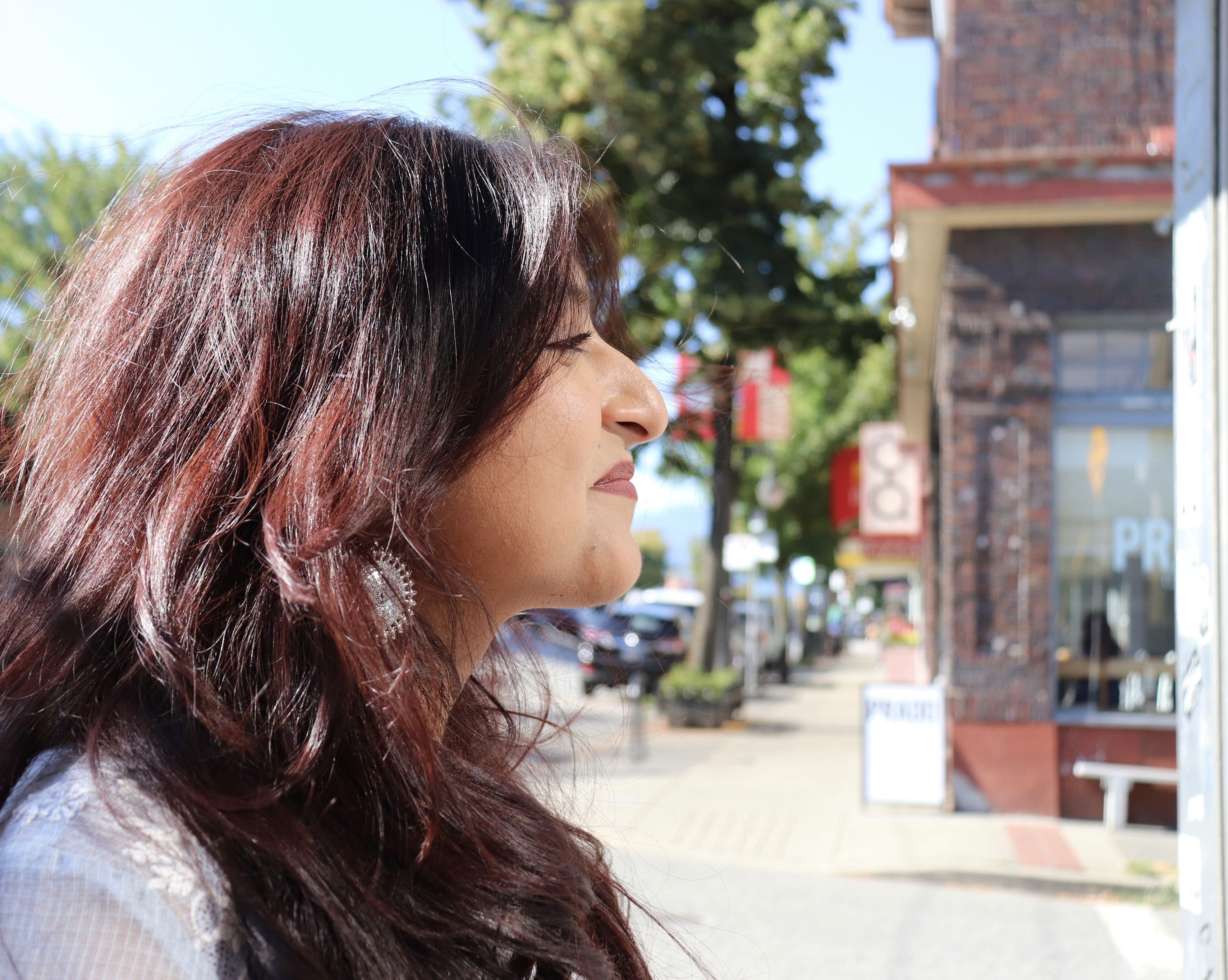 A close-up of a hand wearing multiple decorative rings against a blue background.