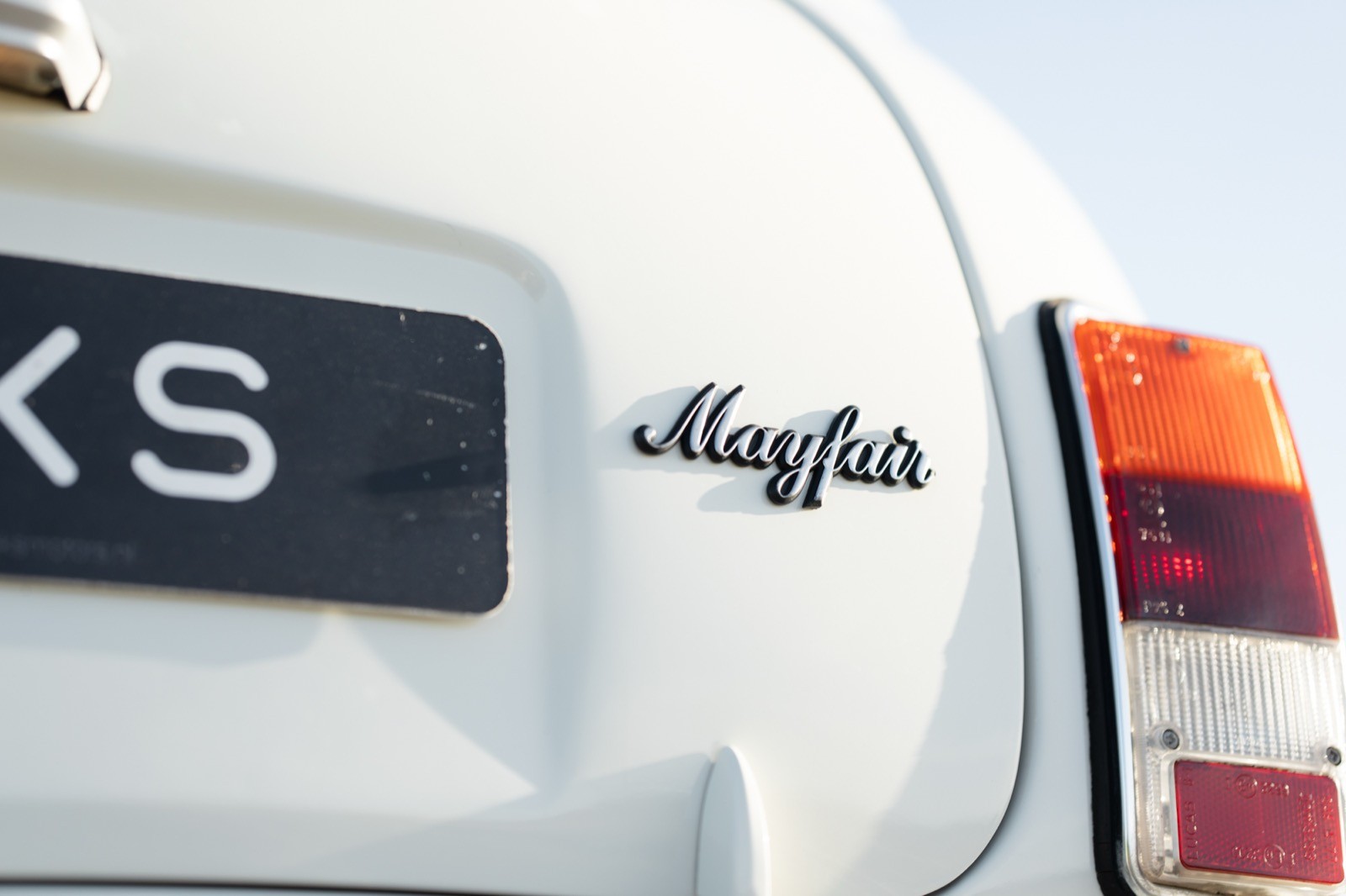 Close-up of the rear of a white car featuring the badge and details of the vehicle model.