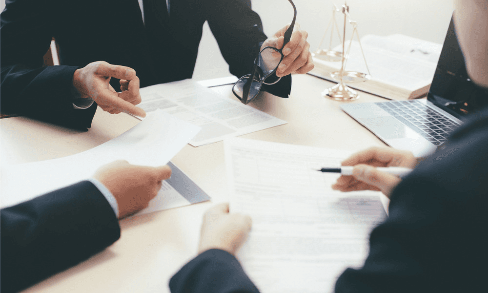 3 people sitting at a table with a laptop and papers