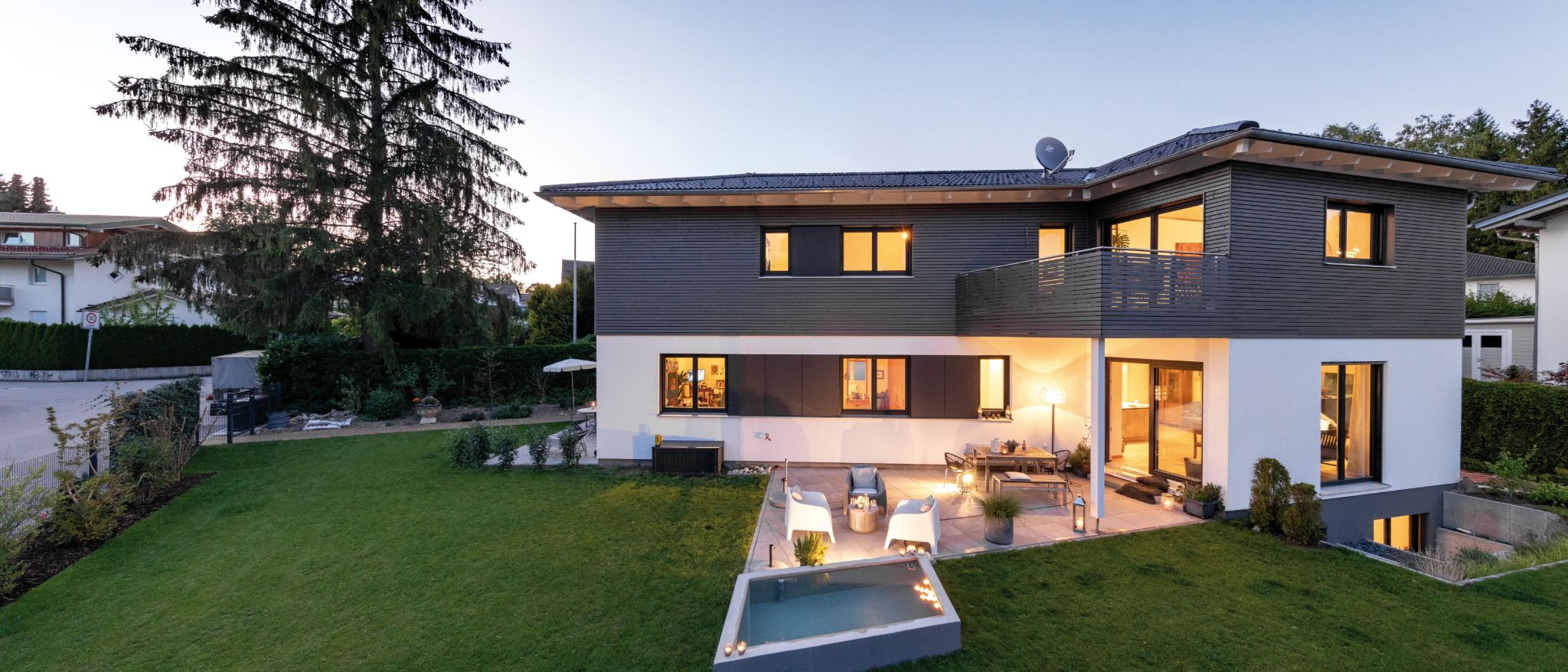 Modernes Haus mit Fassade in Holzoptik und weißem Putz, Terrasse mit Sitzmöbeln und kleinem Pool im Garten.