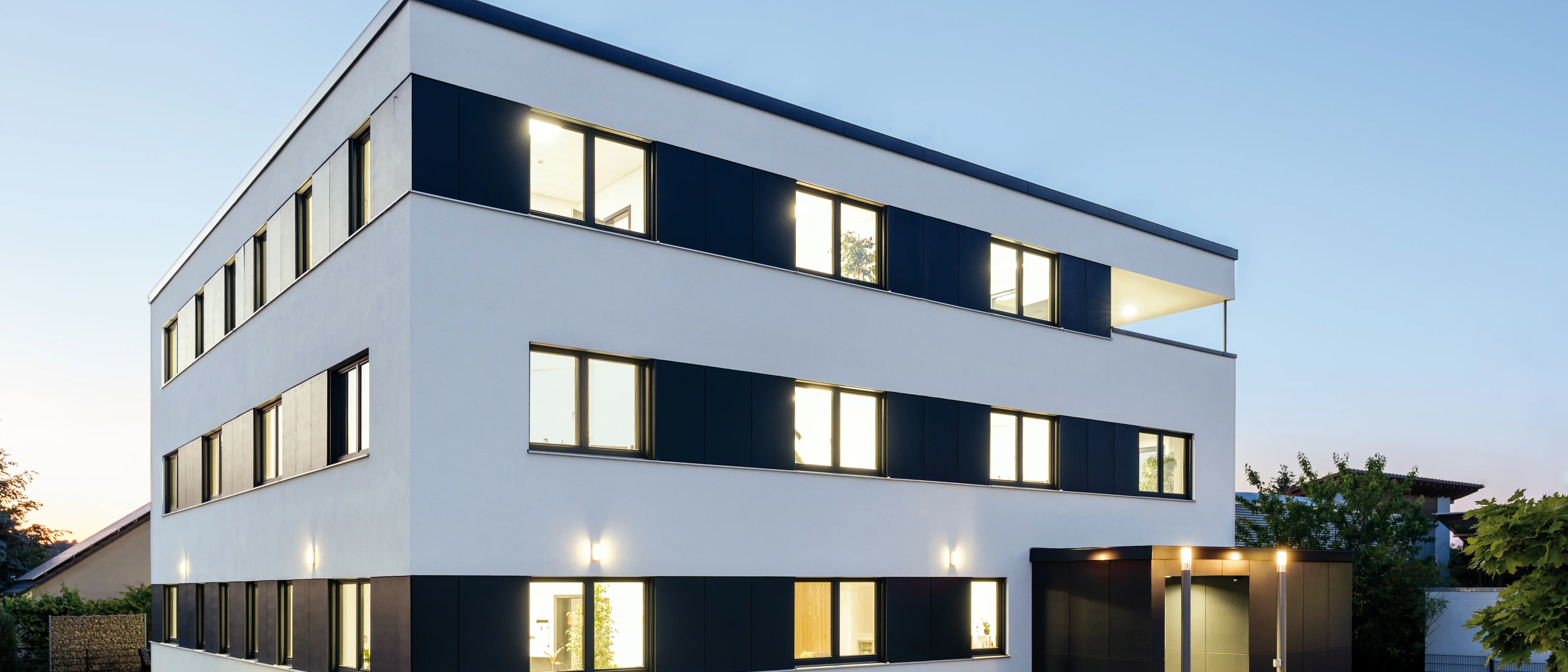 Außenansicht eines weißen Bürogebäudes mit schwarzen Akzenten neben den Fenstern.