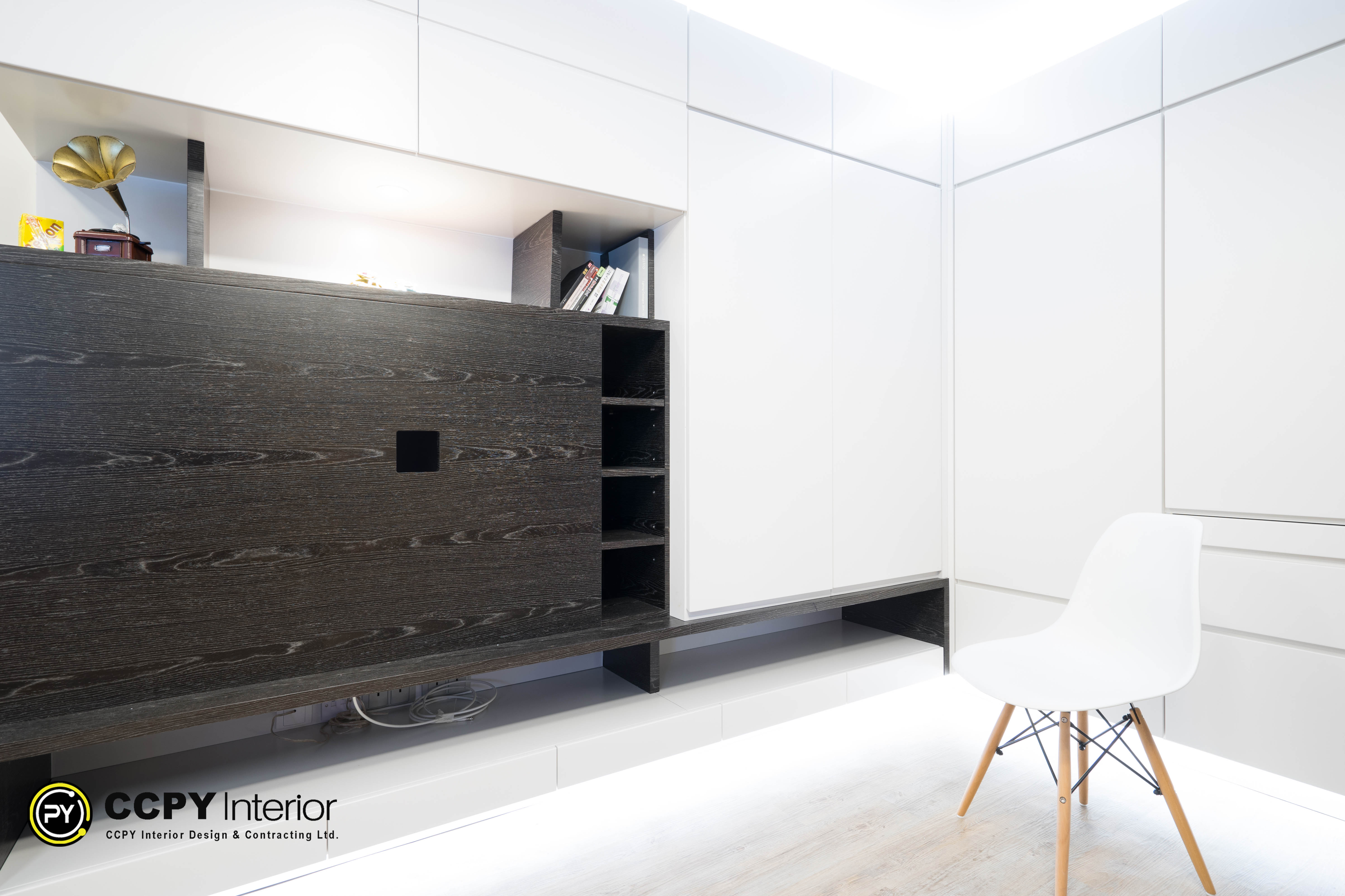 The selected region showcases an interior design project by CCPY Interior, focusing on a contemporary, space-saving living area.Here is a comprehensive breakdown of the design elements, functionality, and aesthetics visible in the image:Design Aesthetics & MaterialsContrast Color Palette: The design pairs dark, textured wood grain panels with smooth, high-gloss white cabinetry to create a sharp, high-fashion contrast.Sleek Minimalism: The handleless push-to-open cabinets offer a clean, seamless look that minimizes visual clutter.Warm Accents: A vintage-style gramophone with a gold horn sits on the left shelf, adding a nostalgic, artistic focal point to the modern backdrop.