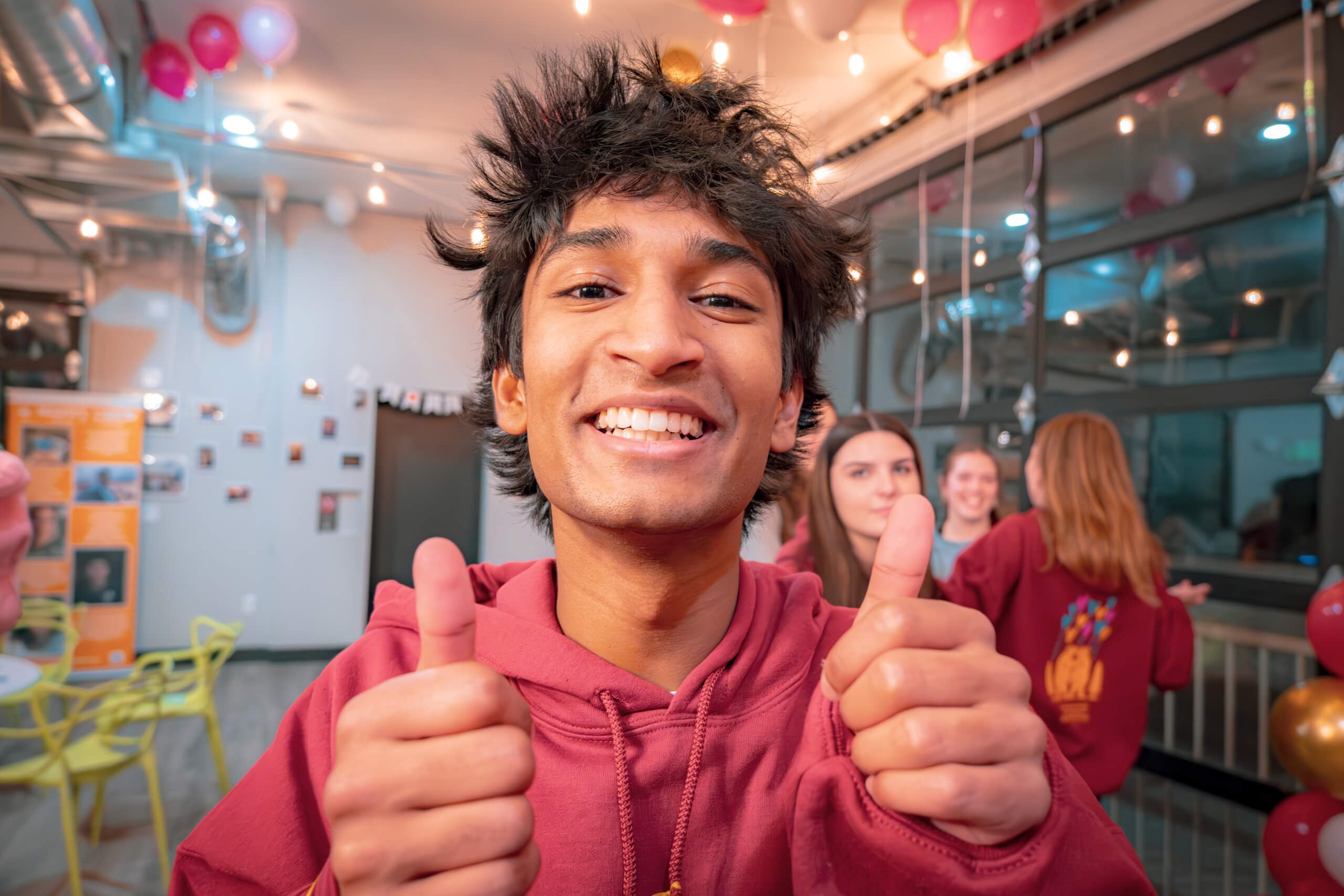 A teenager in a red hoodie giving two thumbs up on a Monday night