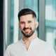 Small portrait photo of a smiling bearded man