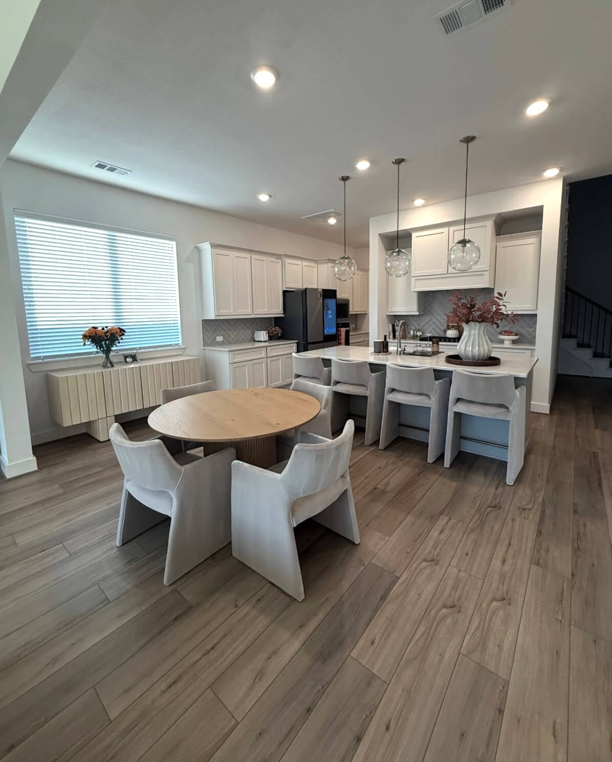 A wide view of a clean open-concept kitchen and dining area with polished hardwood floors, white cabinetry, and spotless countertops after a professional home cleaning.