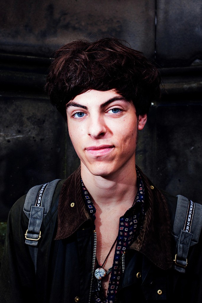 Gosia – Bitter Sweet – sitting on stone steps with an orange resting on her knee under classic balustrades