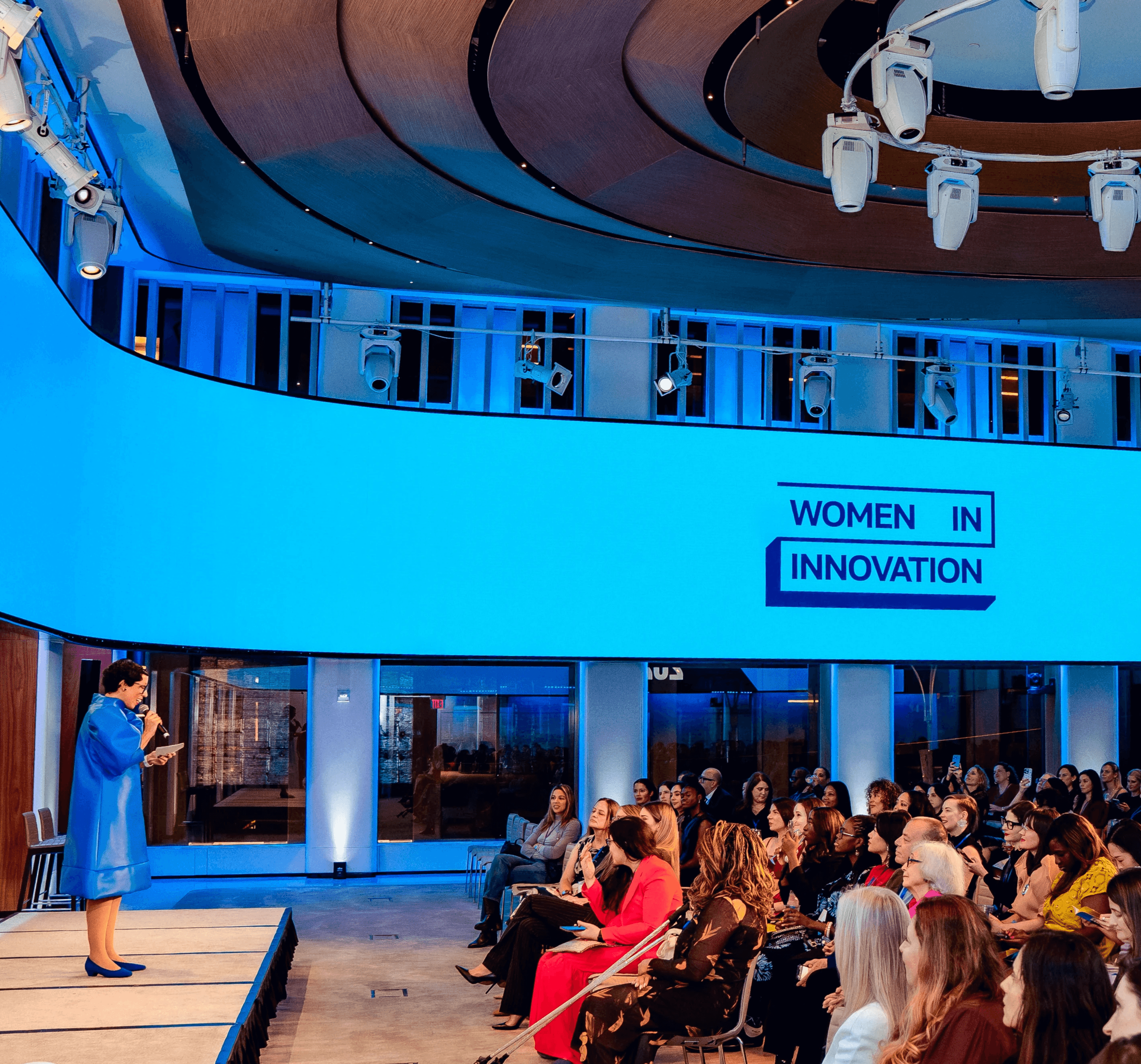 Speaker on stage with the words "Welcome Innovators" on a slide behind her