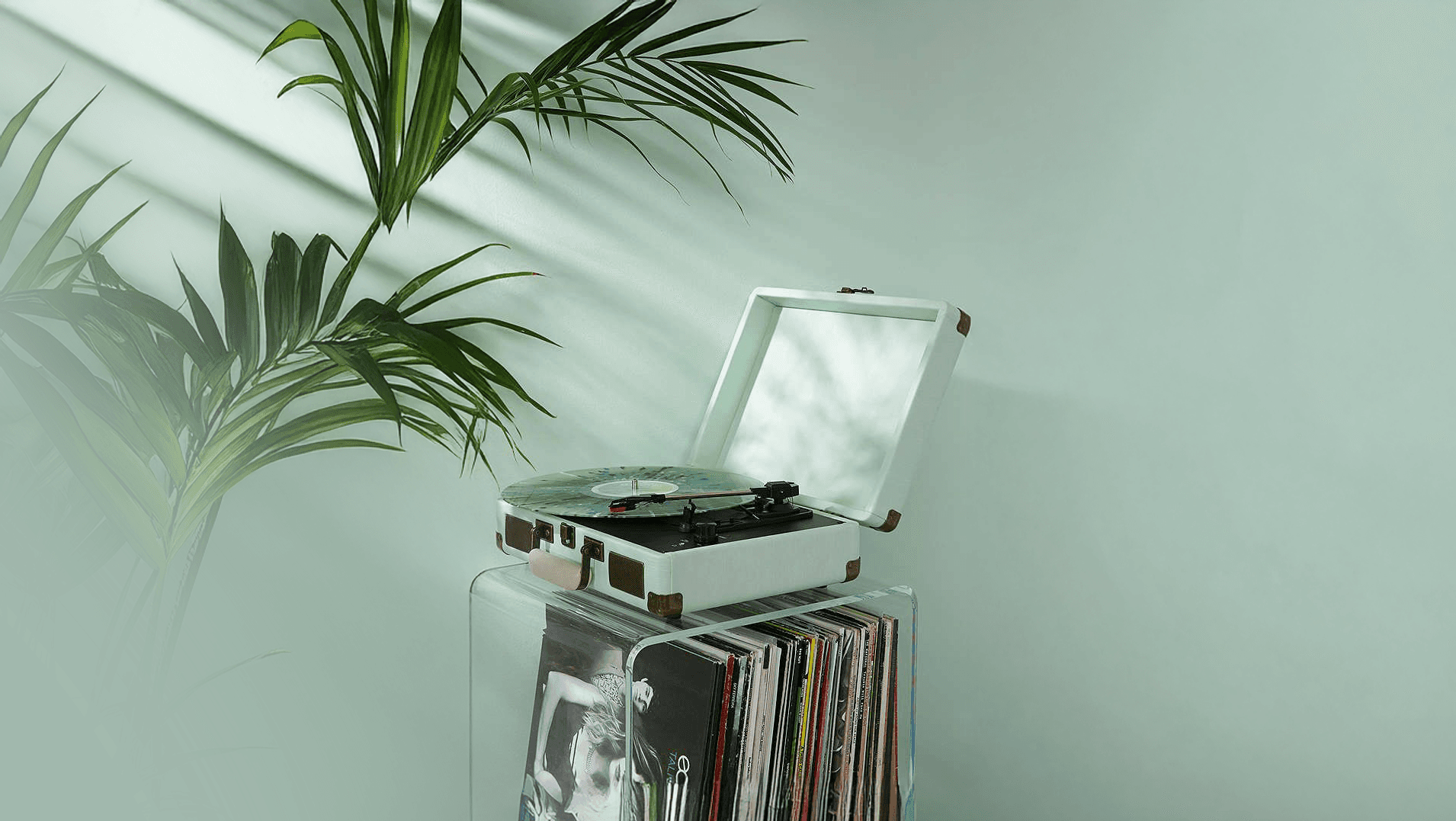 Giradischi con vinili e pianta su fondo verde